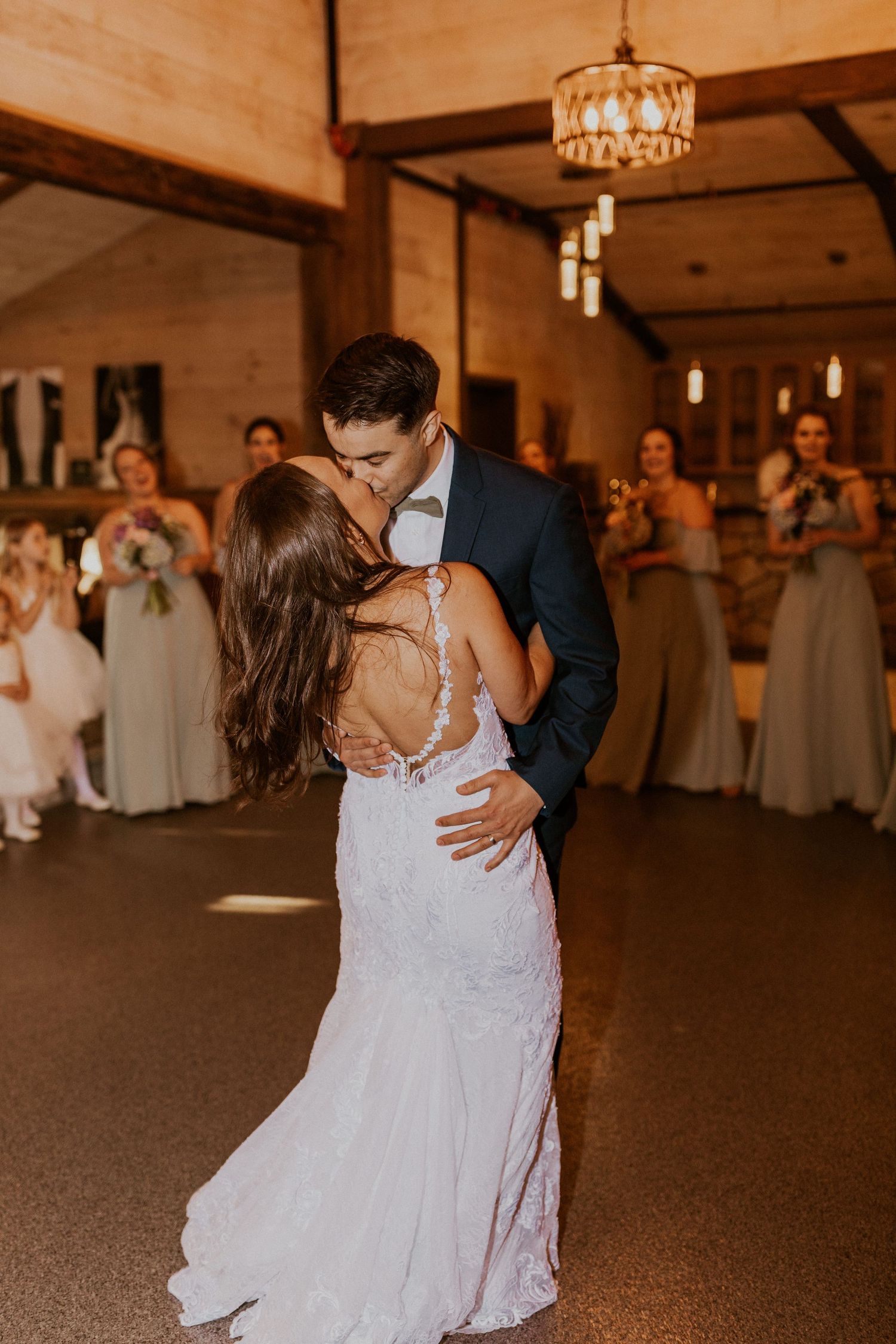 Couple shares a tender moment during their wedding dance in a rustic venue with pendant lights.