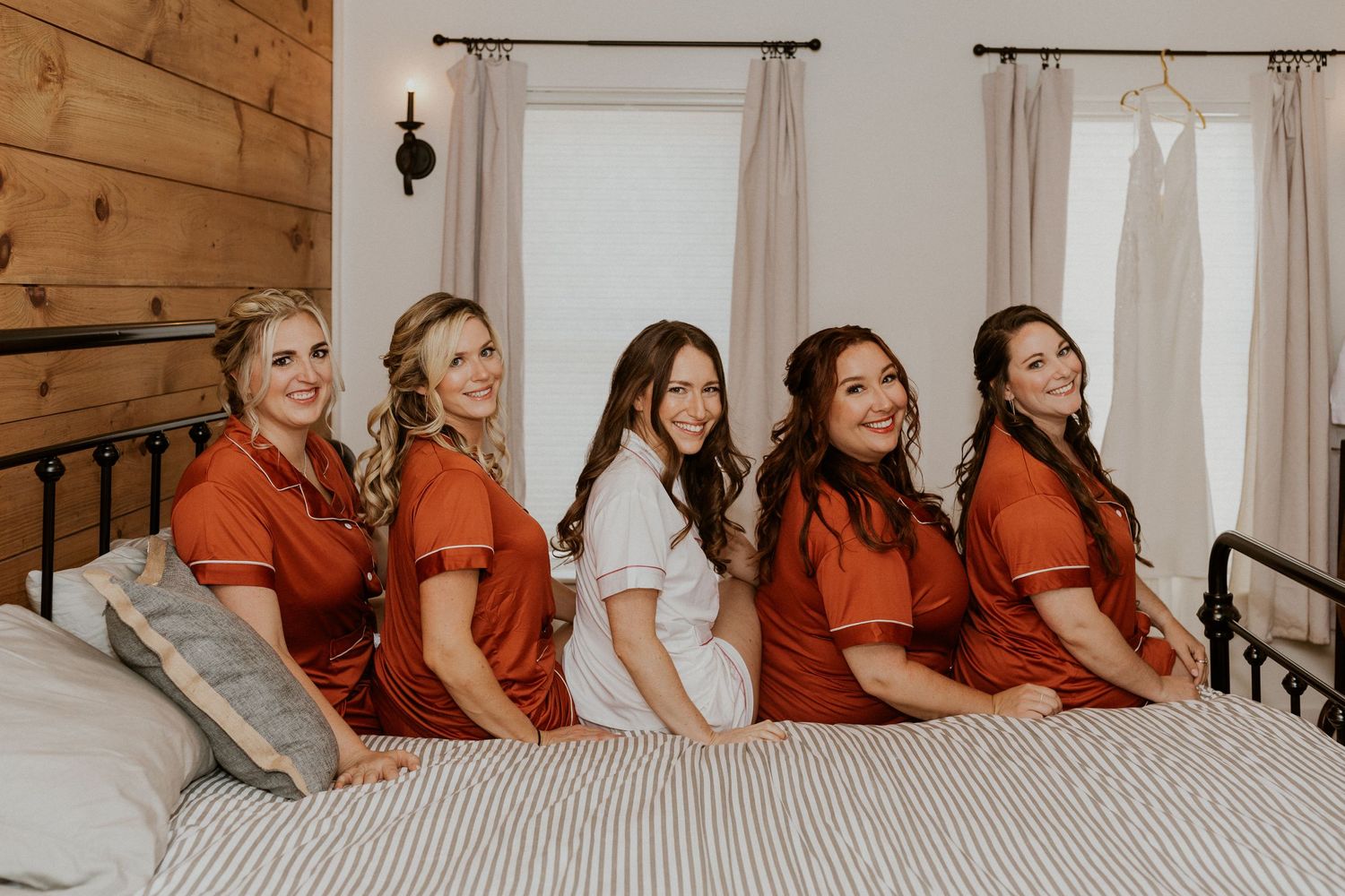 Briana and her bridesmaids sit together on the bed for a fun pajama photo before getting dressed.