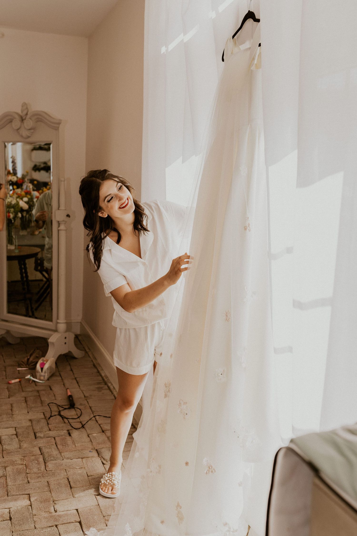 Playful pre-wedding moments in a bright room with white curtains.