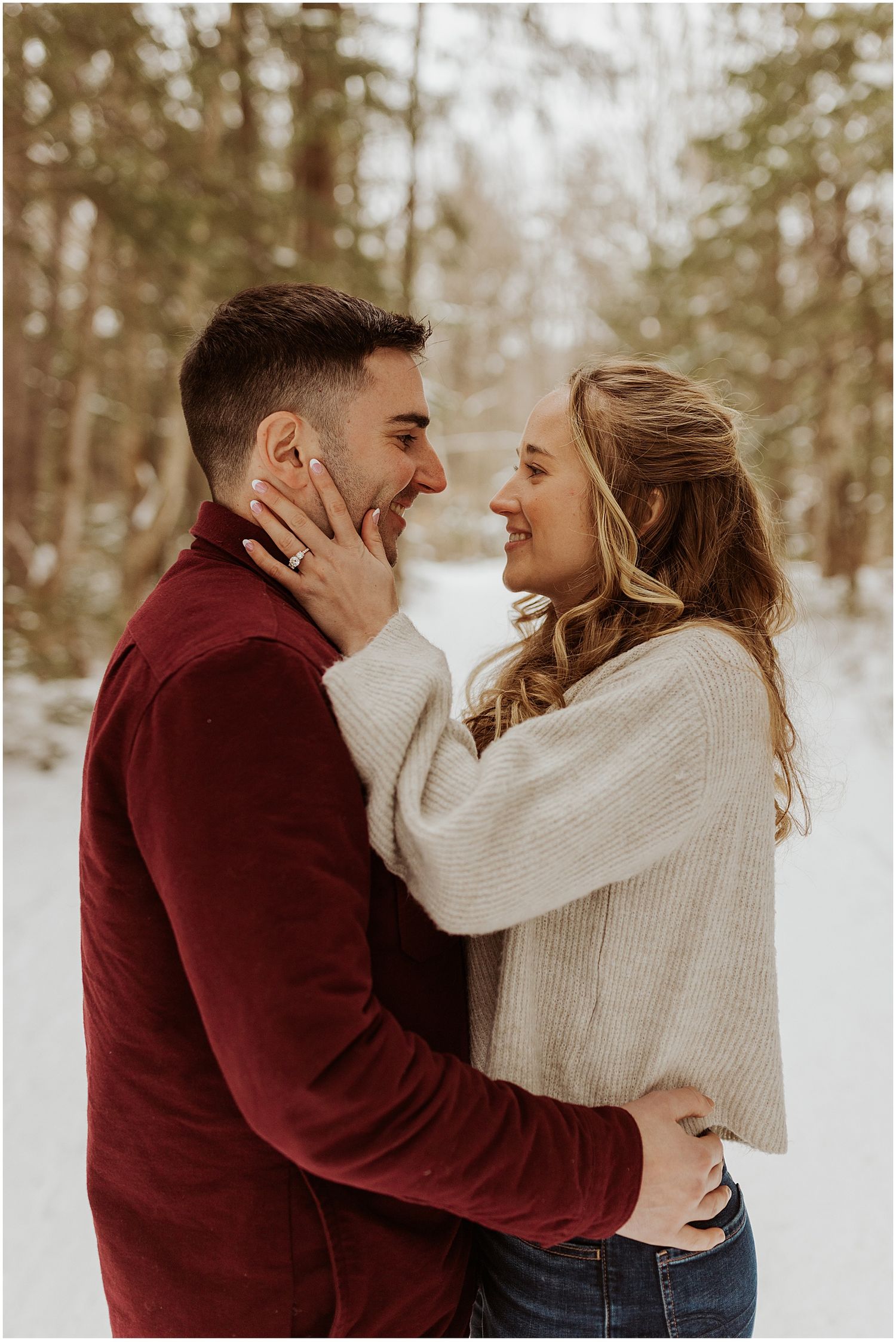 NH couple taking winter engagement pictures in the woods