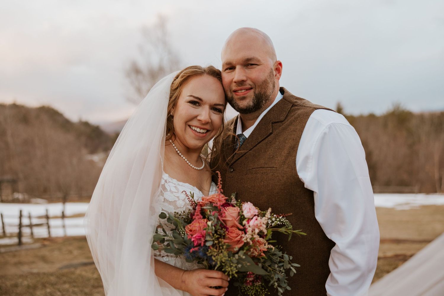 Winter wedding portrait session in a snow-covered field during golden hour.