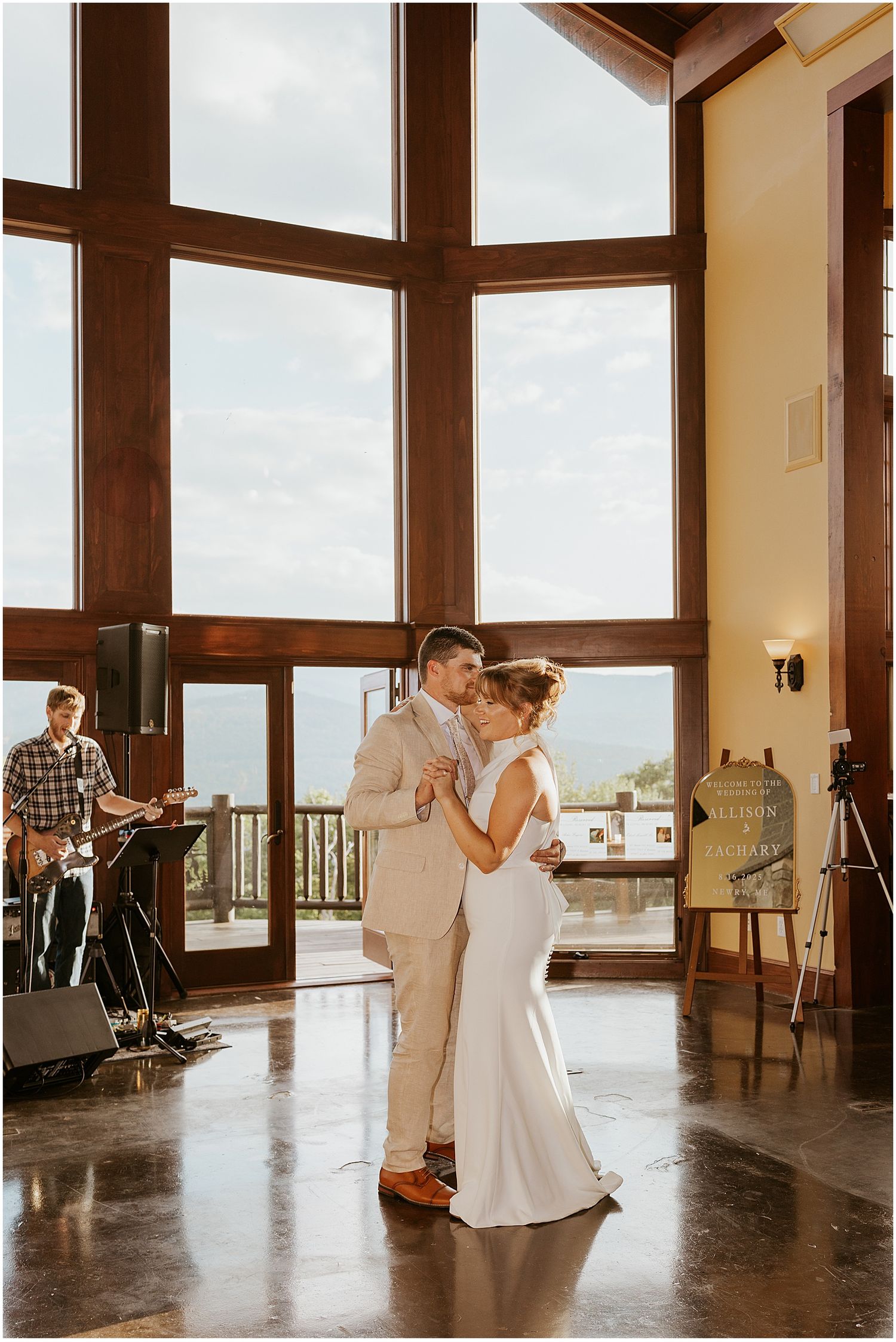 A romantic first dance between newlyweds in a spacious venue with large windows overlooking a scenic view at a VRBO wedding
