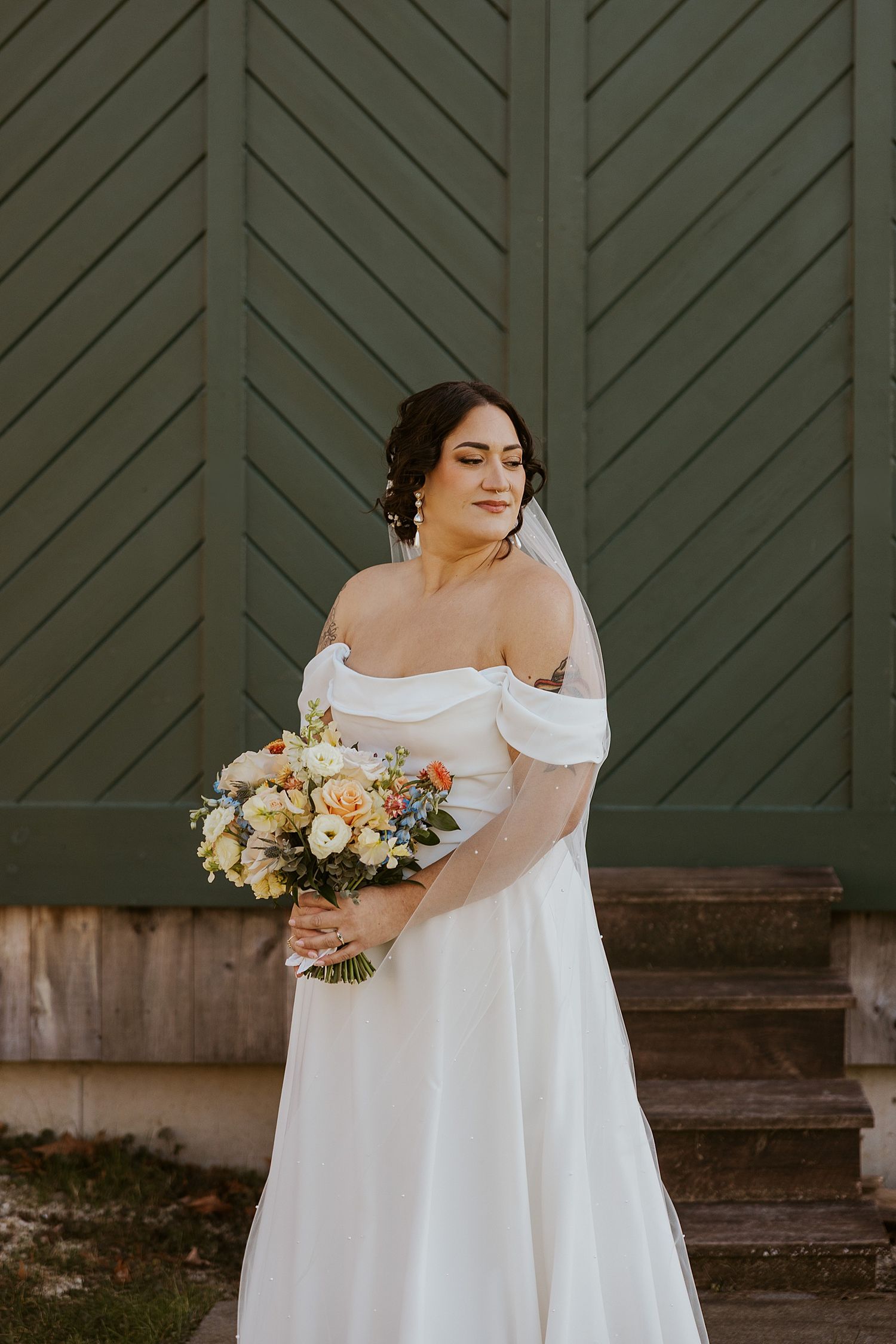 Bride in an off-the-shoulder gown holding a bouquet of peach and cream flowers for her fall New Hampshire wedding