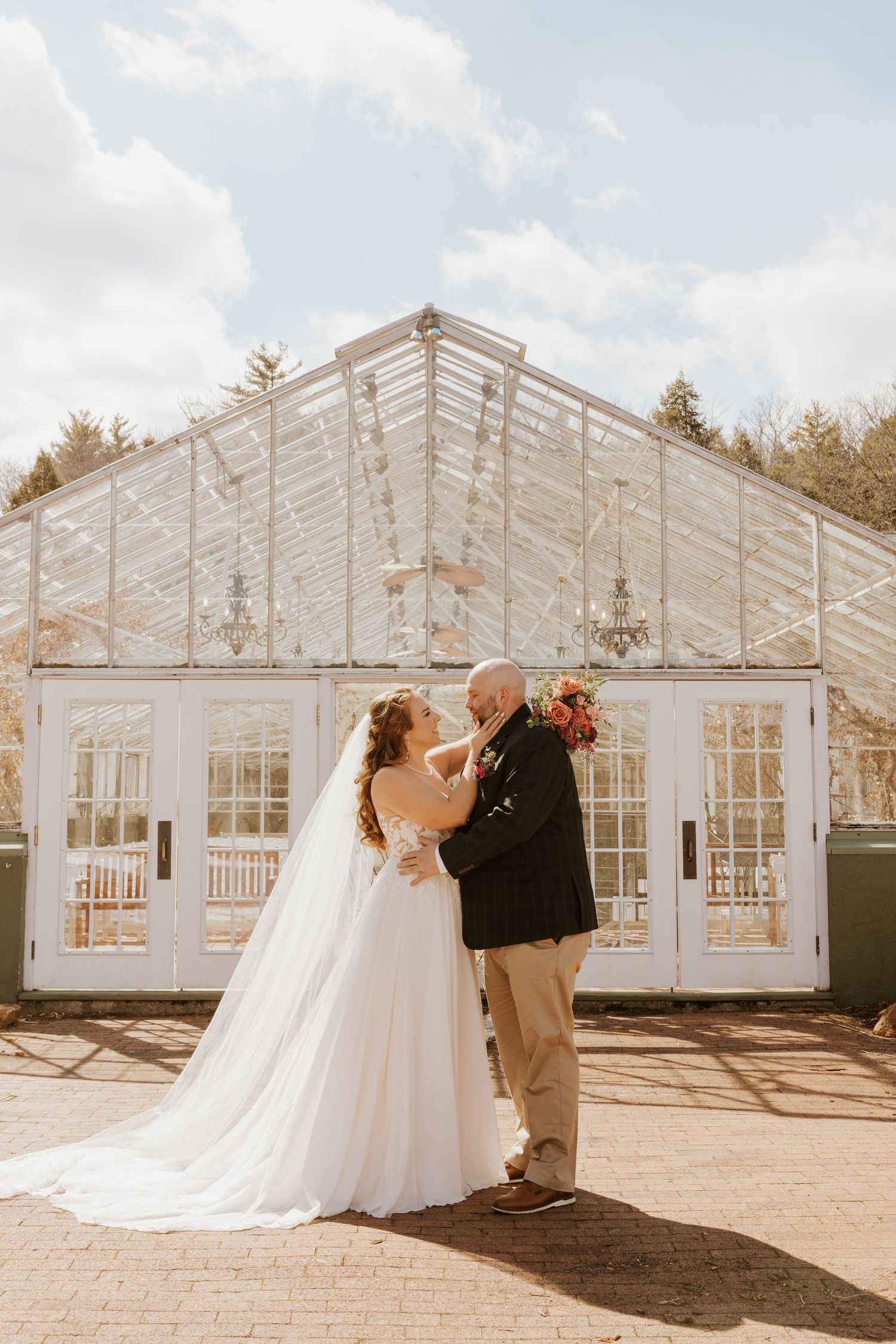 A beautiful greenhouse wedding venue with white framed windows and elegant architecture in natural sunlight.