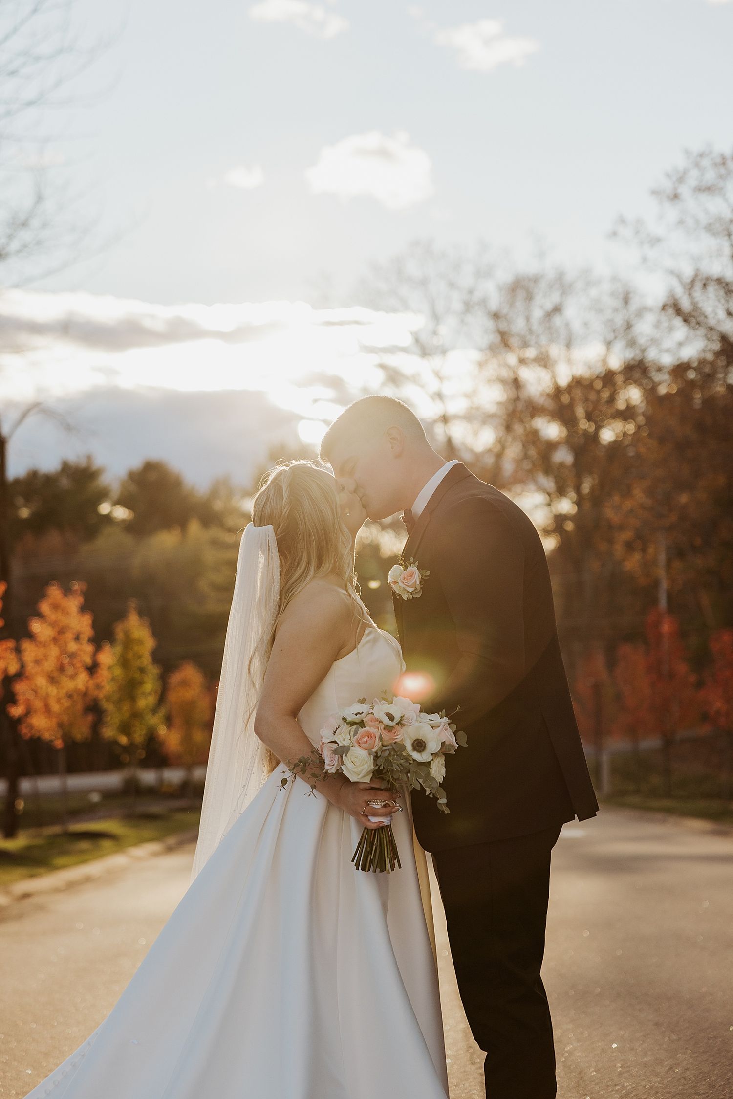 Bride and groom kissing in the golden hour sunset light at their fall New Hampshire wedding at Hyla Brook Estate
