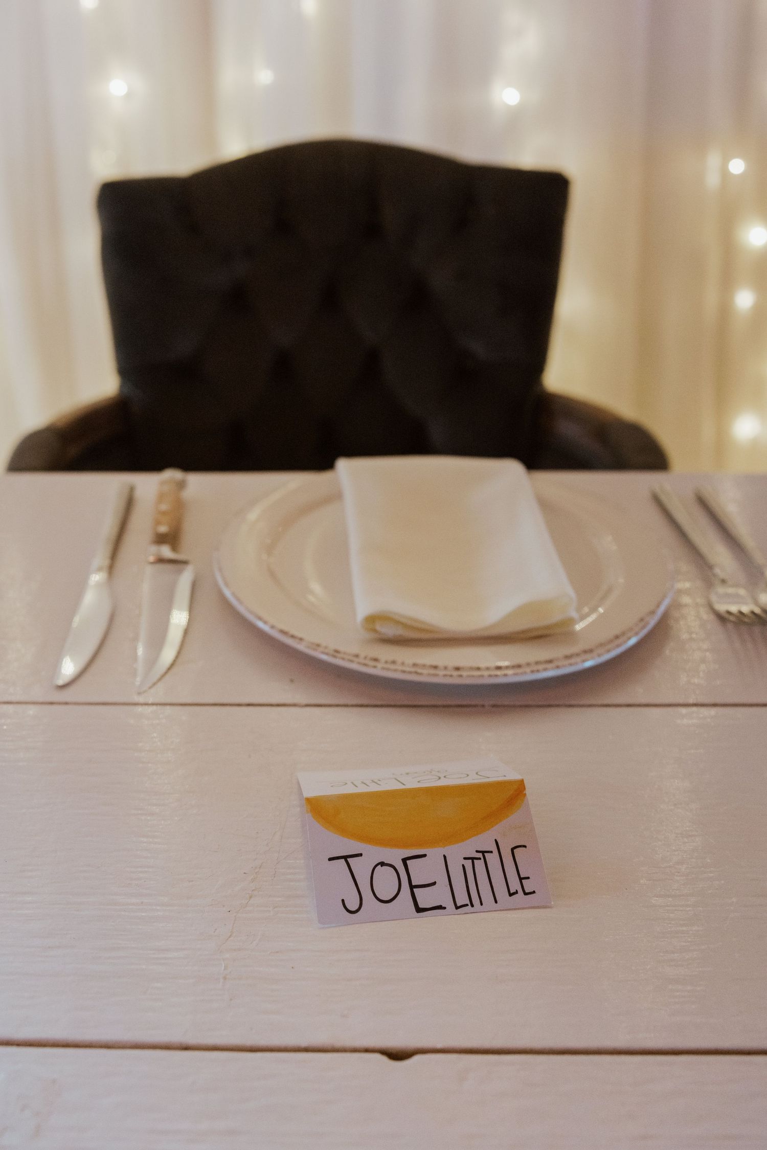 Elegant white wedding place setting with Joe Little name card at reception table.