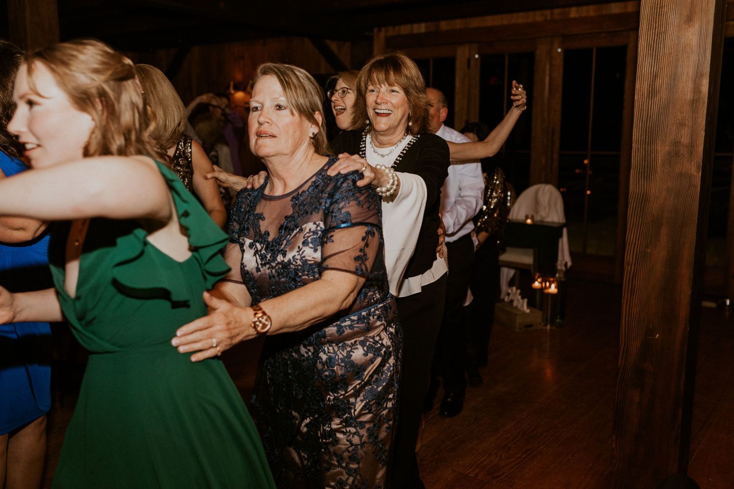 A train of wedding guests dancing together at the wedding reception.