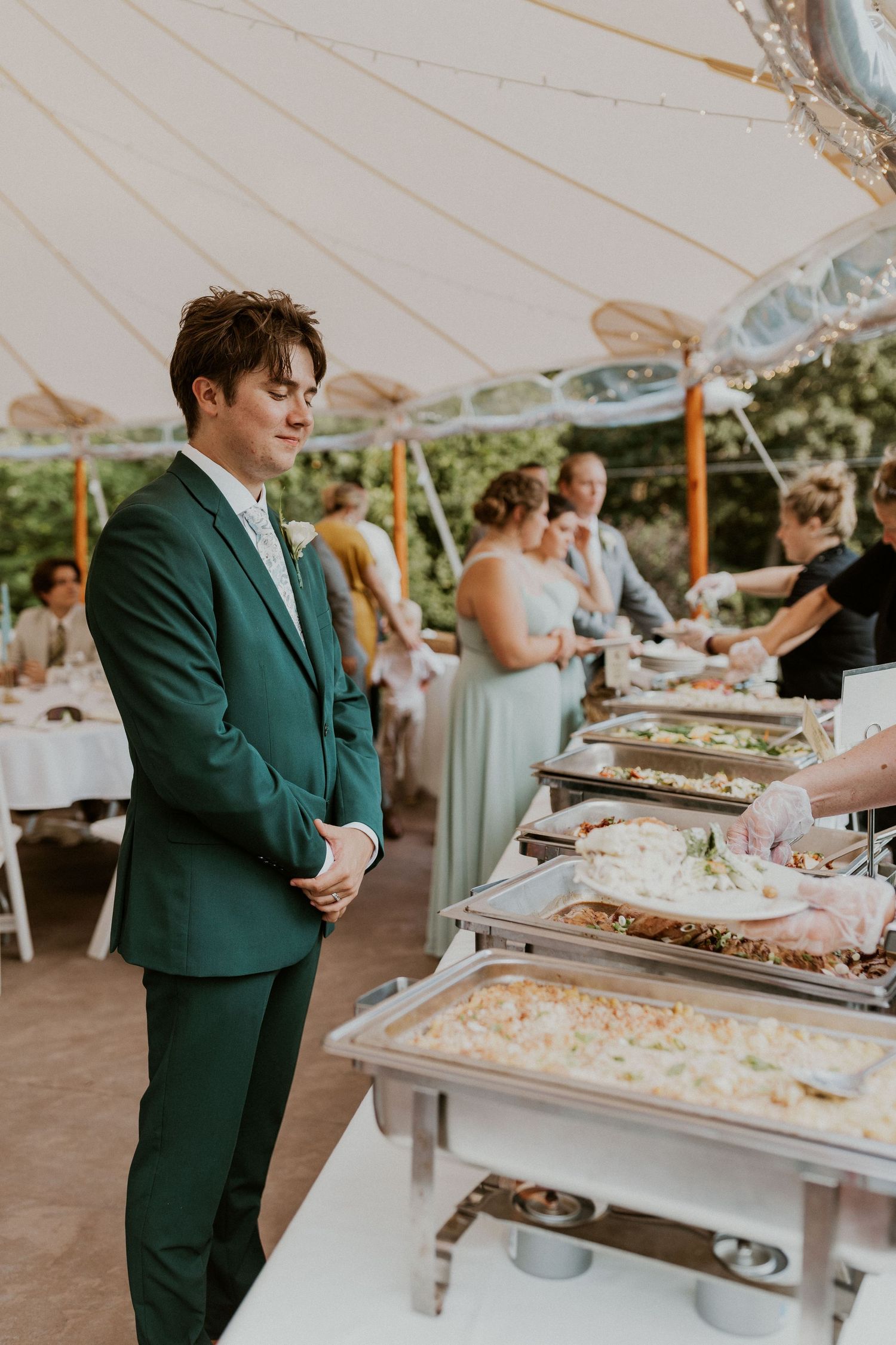 Wedding reception buffet line with guests in formal attire serving themselves.