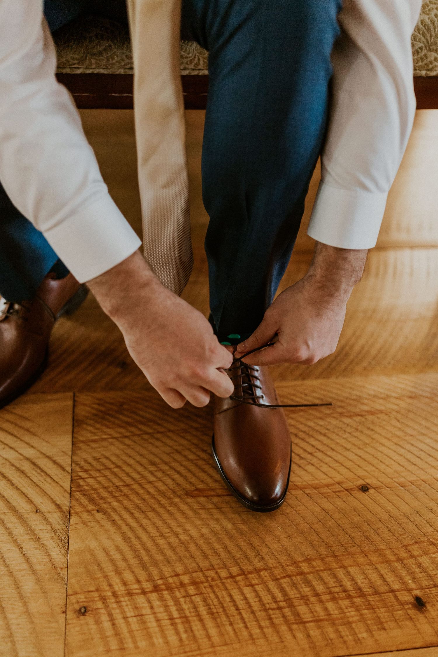 A detail photograph of Daniel tying his shoe as he prepares for the wedding.
