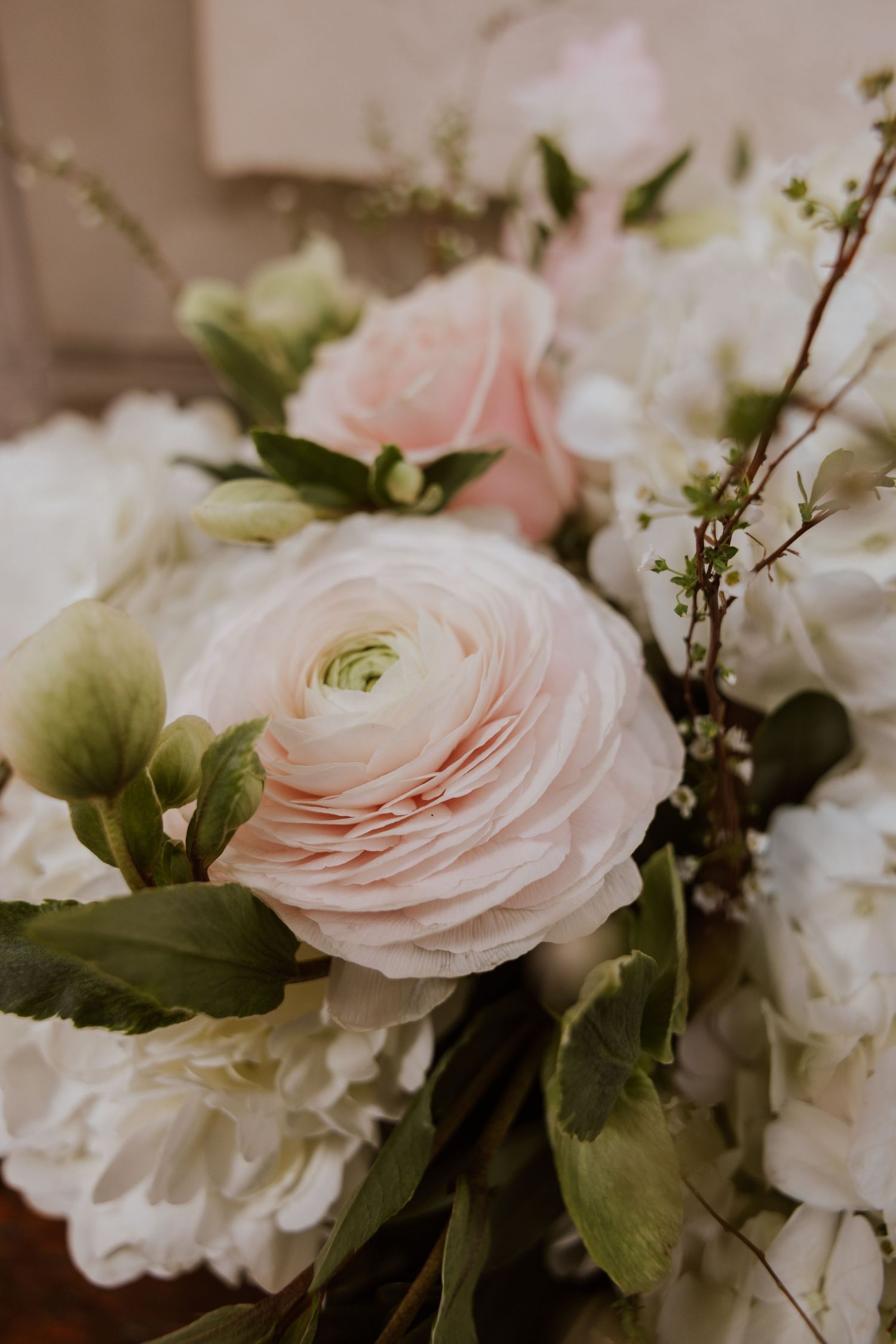 Delicate pink roses and white flowers arranged in an elegant floral display with soft green foliage.