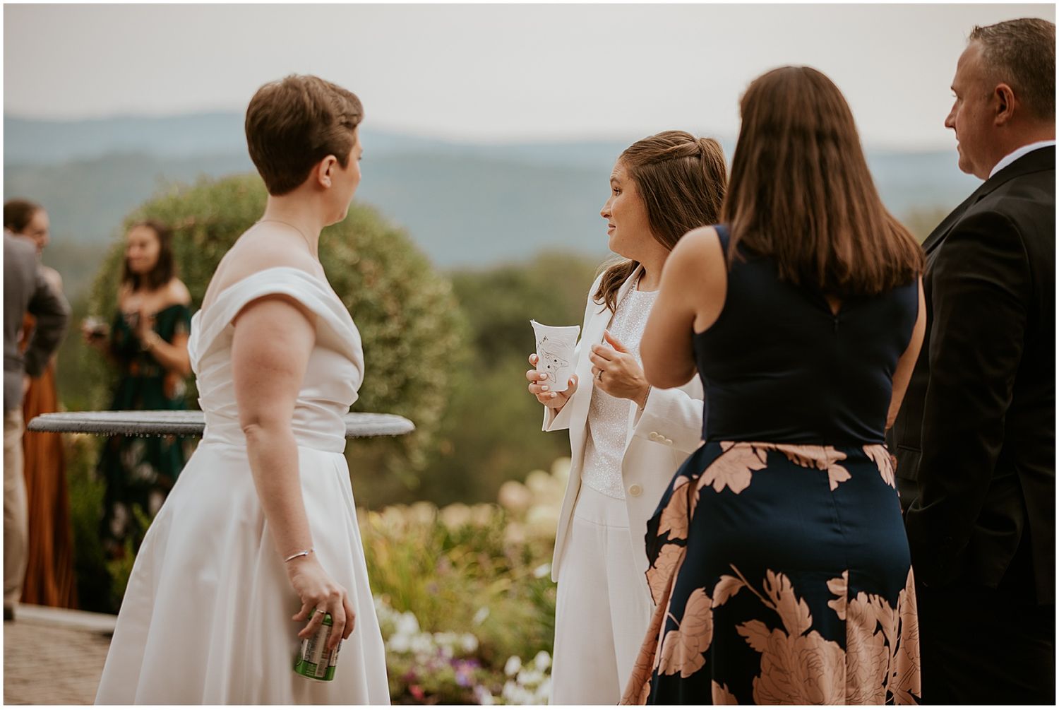 Brides mingling with their guests at an outdoor cocktail hour reception at their wedding in the NH mountains