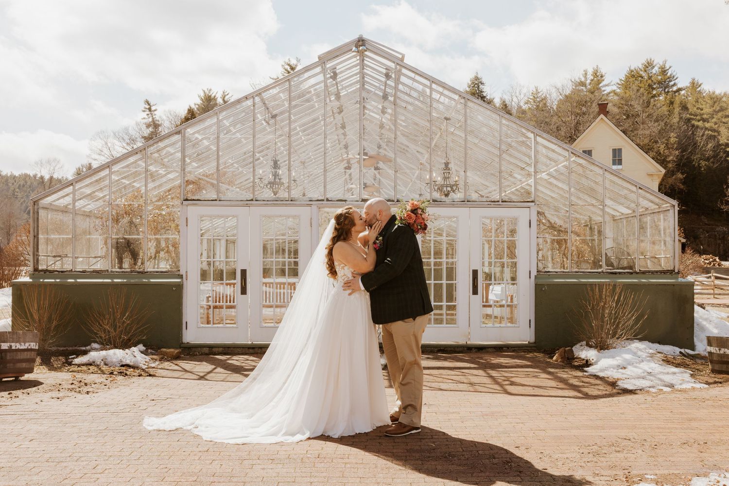 A couple shares a romantic moment outside a beautiful glass greenhouse venue on their wedding day.
