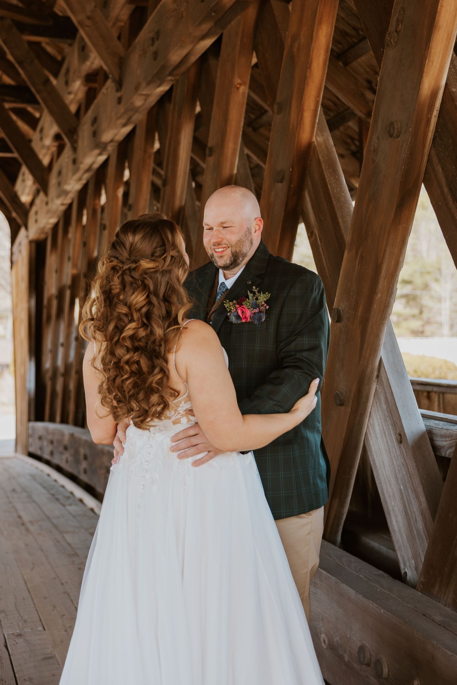 A romantic first look moment between newlyweds inside a rustic covered wooden bridge.
