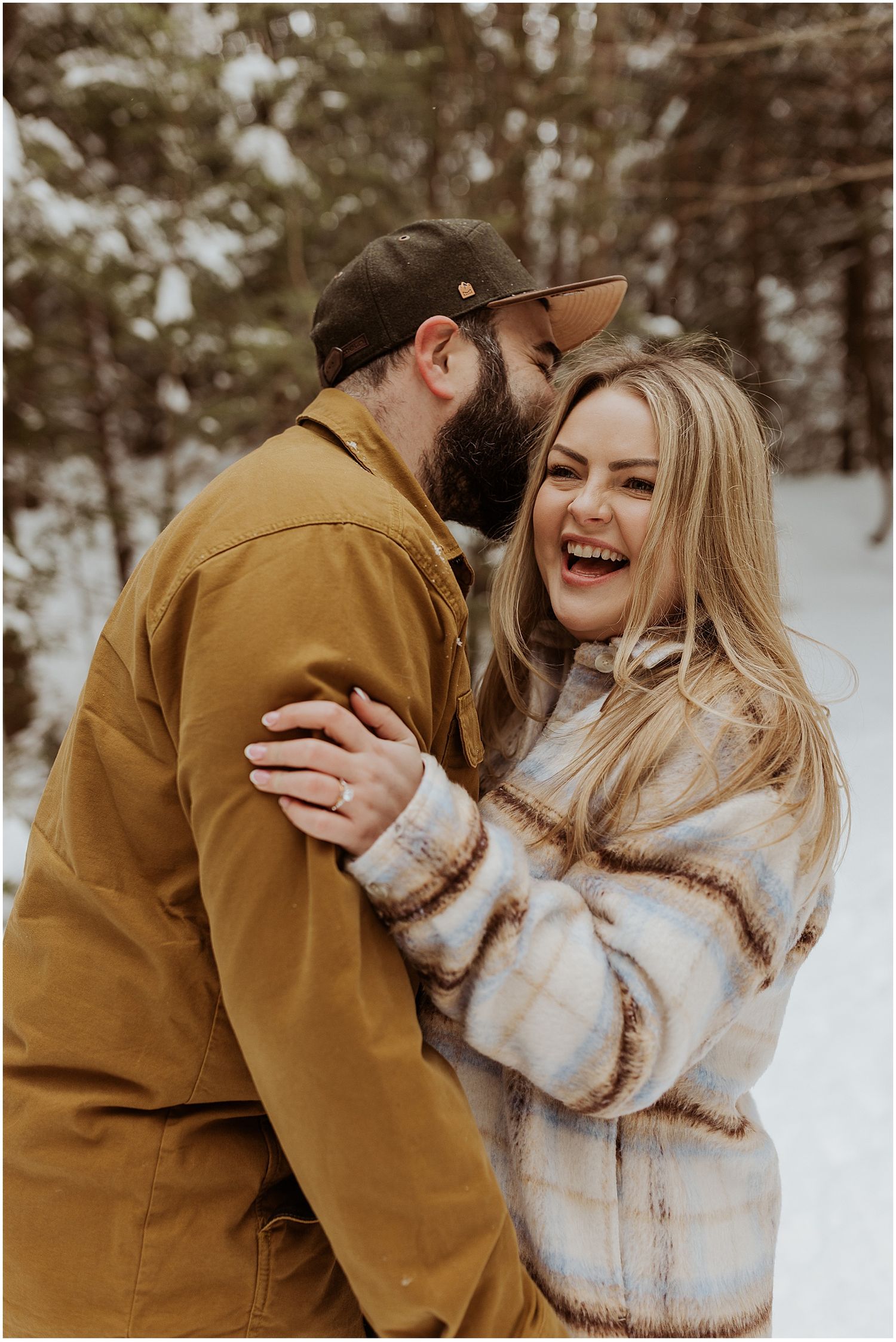 Couple taking engagement pictures in the NH mountains wearing winter engagement photo outfits