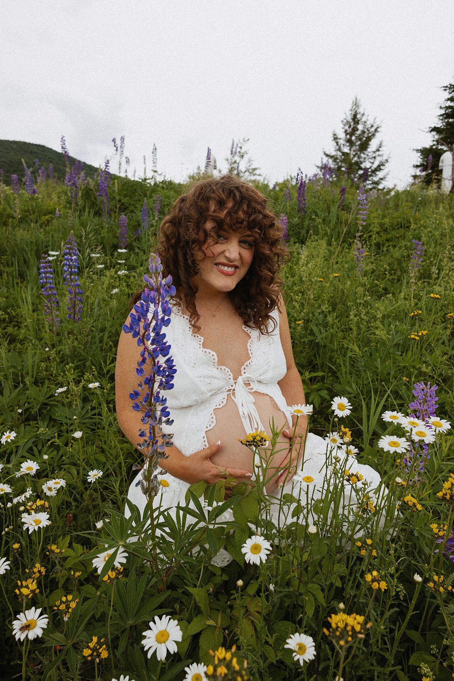 Pregnant woman taking motherhood photos in a wildflower field in New Hampshire