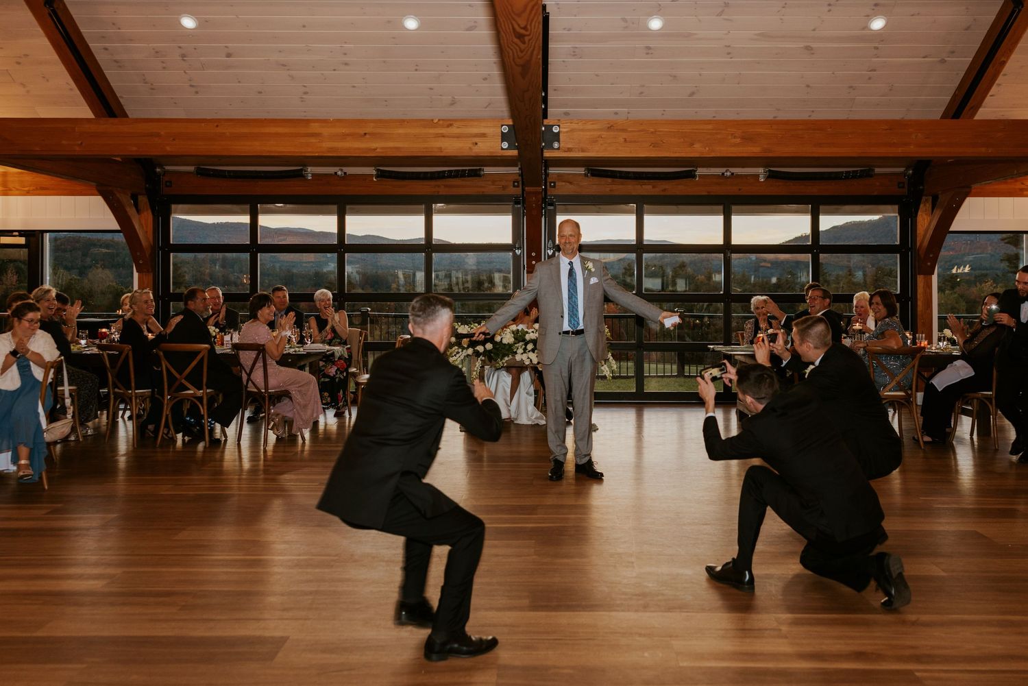 Groomsmen perform fun surprise dance routine for groom at wedding reception on dance floor.