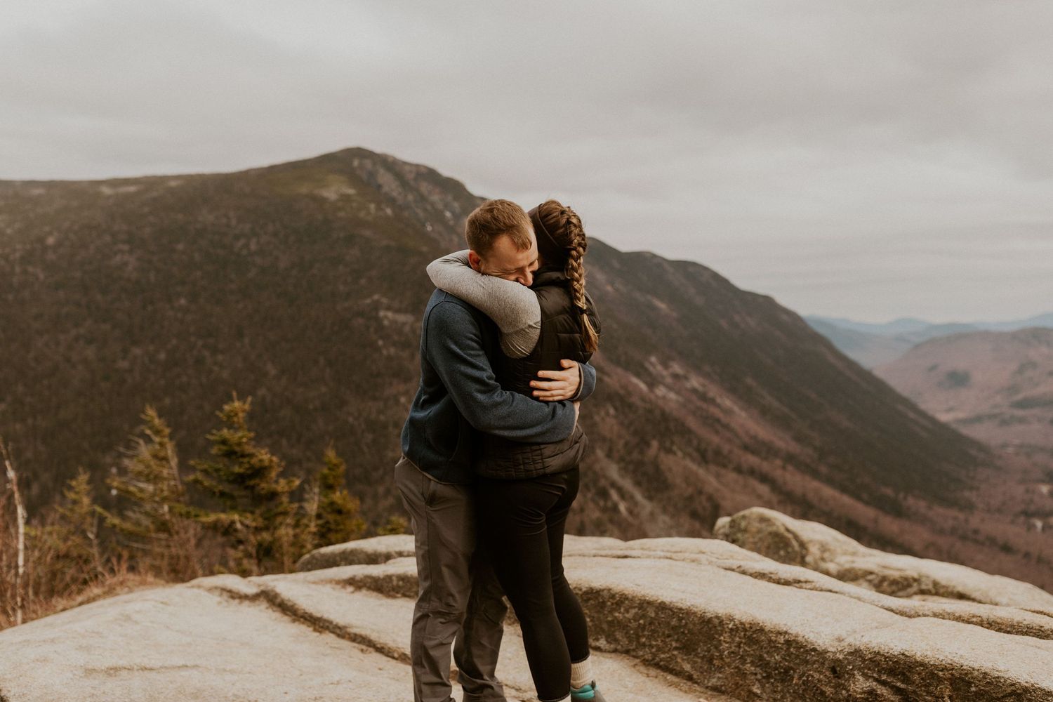 Newly engaged couple embracing each other on top of Mount Willard in the White Mountains of New Hampshire.