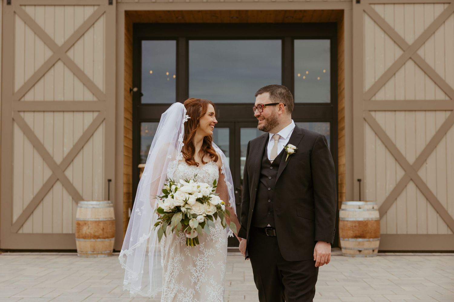 Newlyweds share a romantic moment in front of rustic barn doors during their wedding celebration.