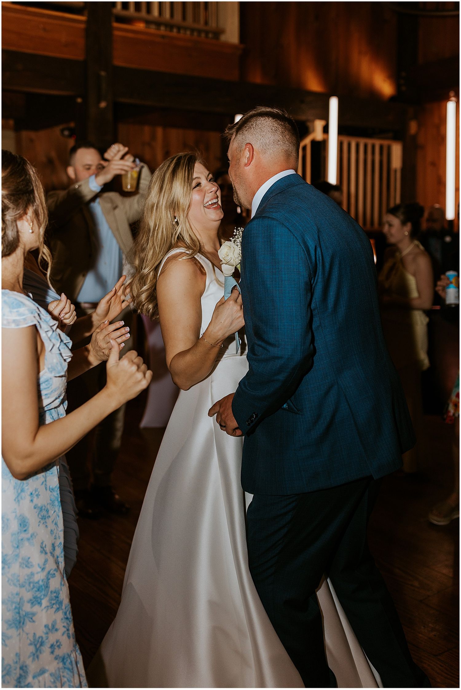 A couple shares a romantic dance moment at a dimly lit indoor wedding reception.