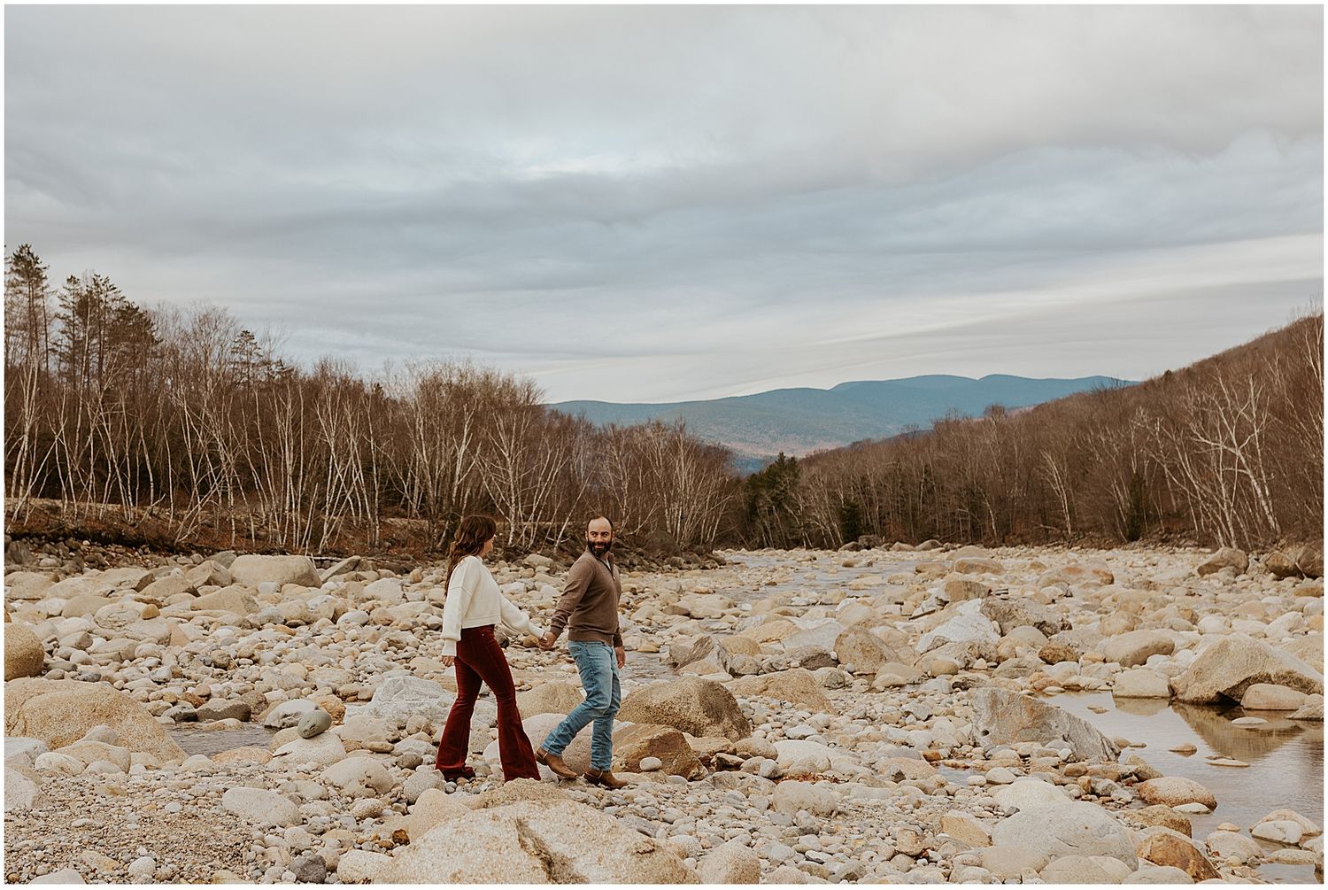 Couple taking engagement photos by the Pemi river in the NH White Mountains