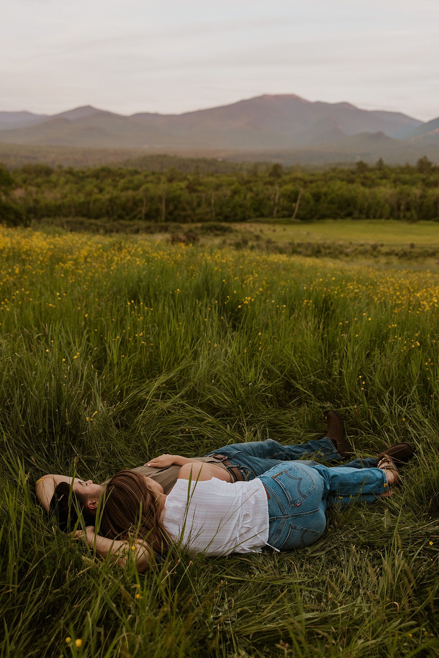 New Hampshire couple laying in a field together taking engagement photos