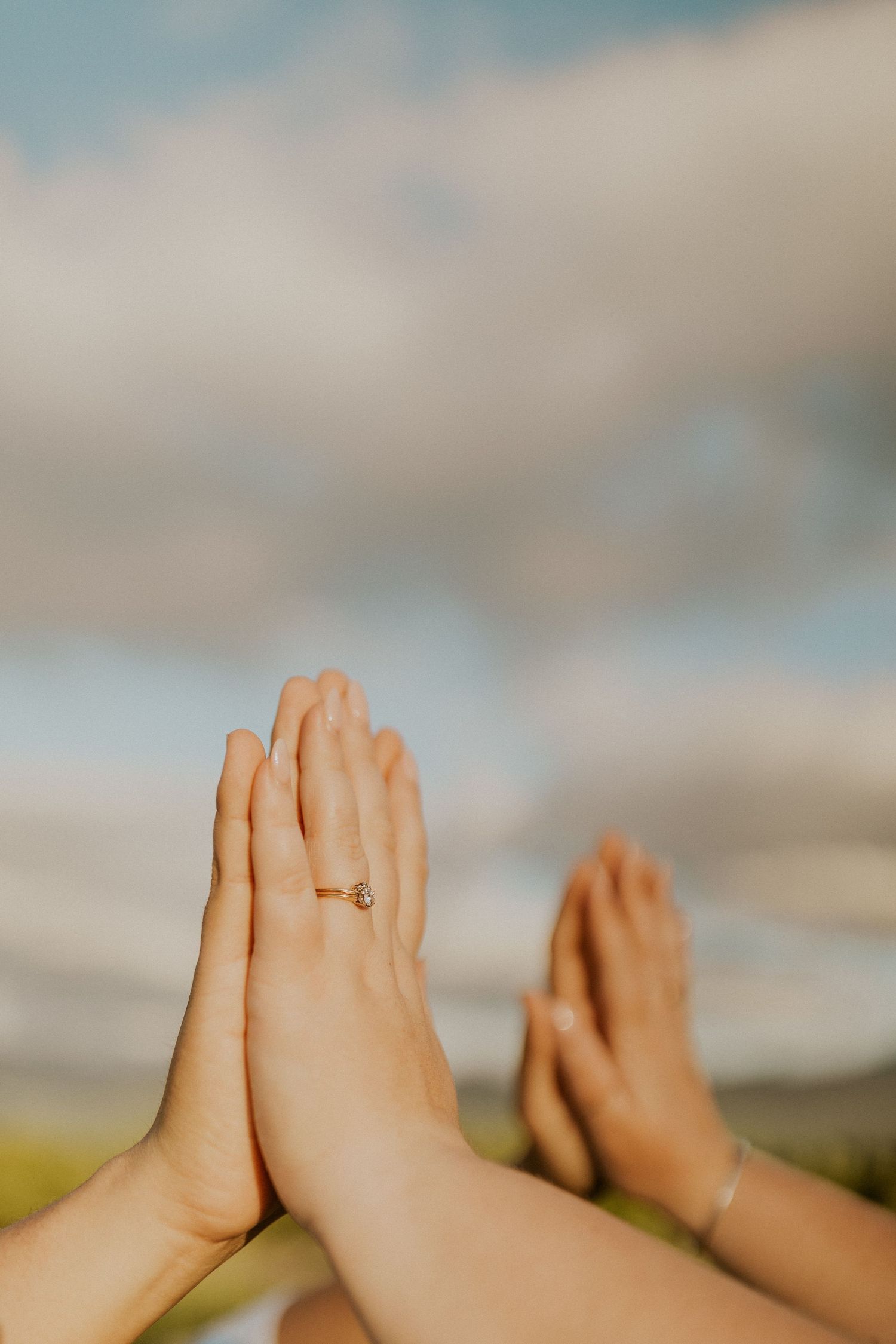Terise and Jose's hands against each other with a sky as the backdrop.