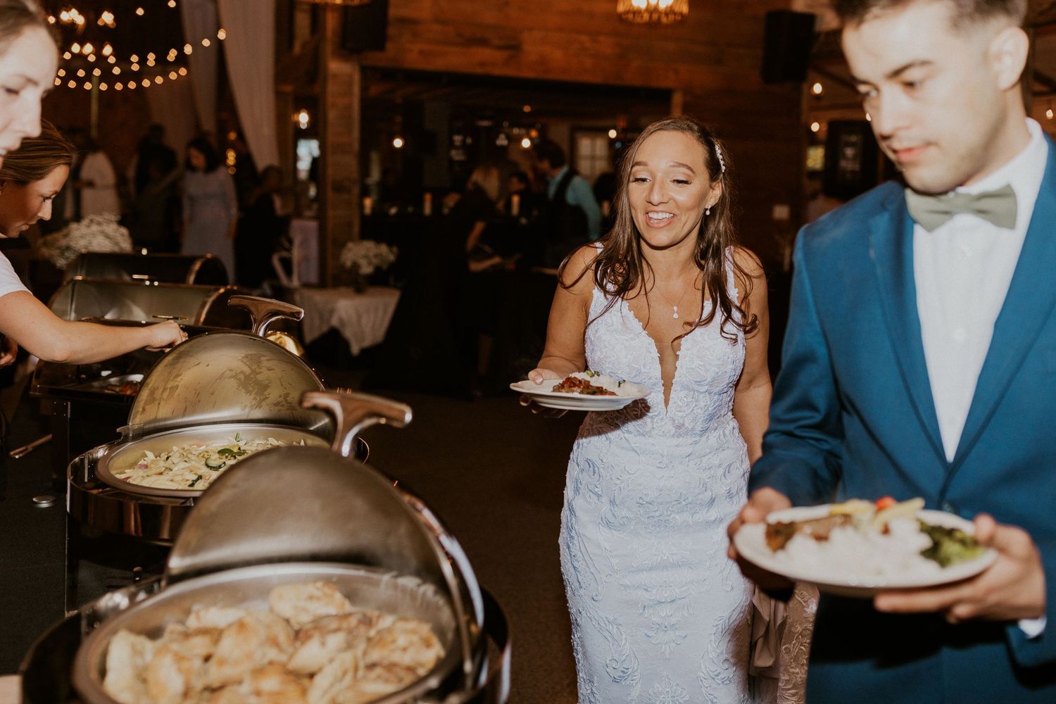 Wedding reception scene in a rustic barn venue with string lights and white drapes creating a romantic atmosphere.