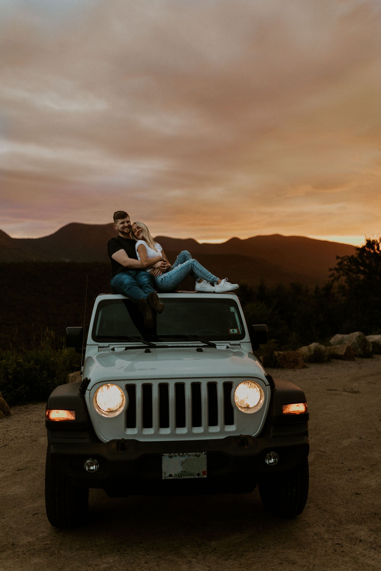 Paige and Justin cuddling up together on top of her jeep on the Kancamagus HIghway during their adventure photoshoot.