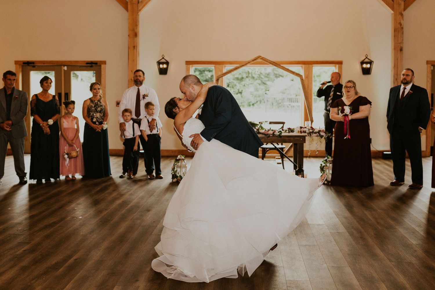Elegant wedding reception venue with rustic wooden beams and natural lighting showcases guests mingling.