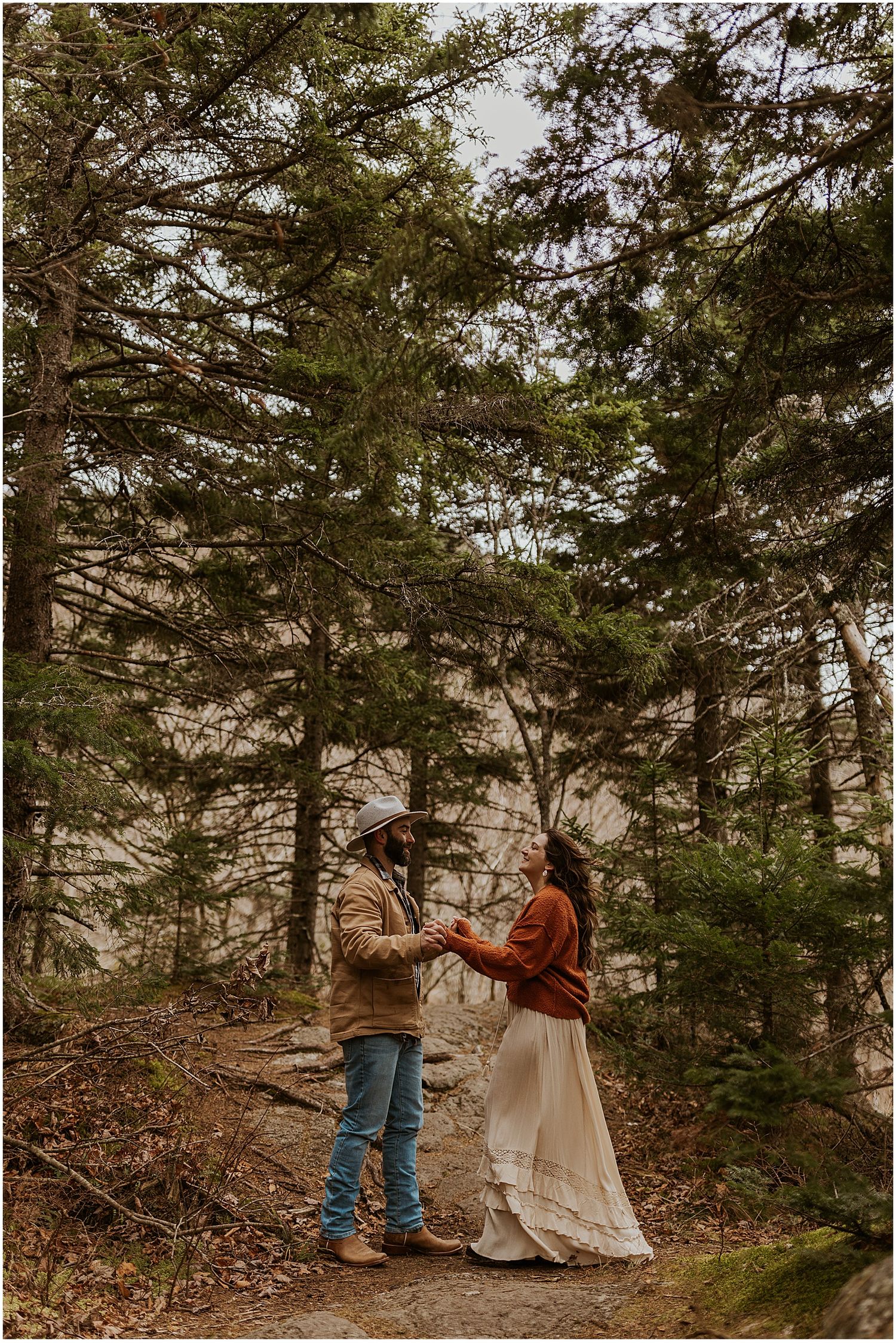 Couple taking engagement photos in the woods in NH