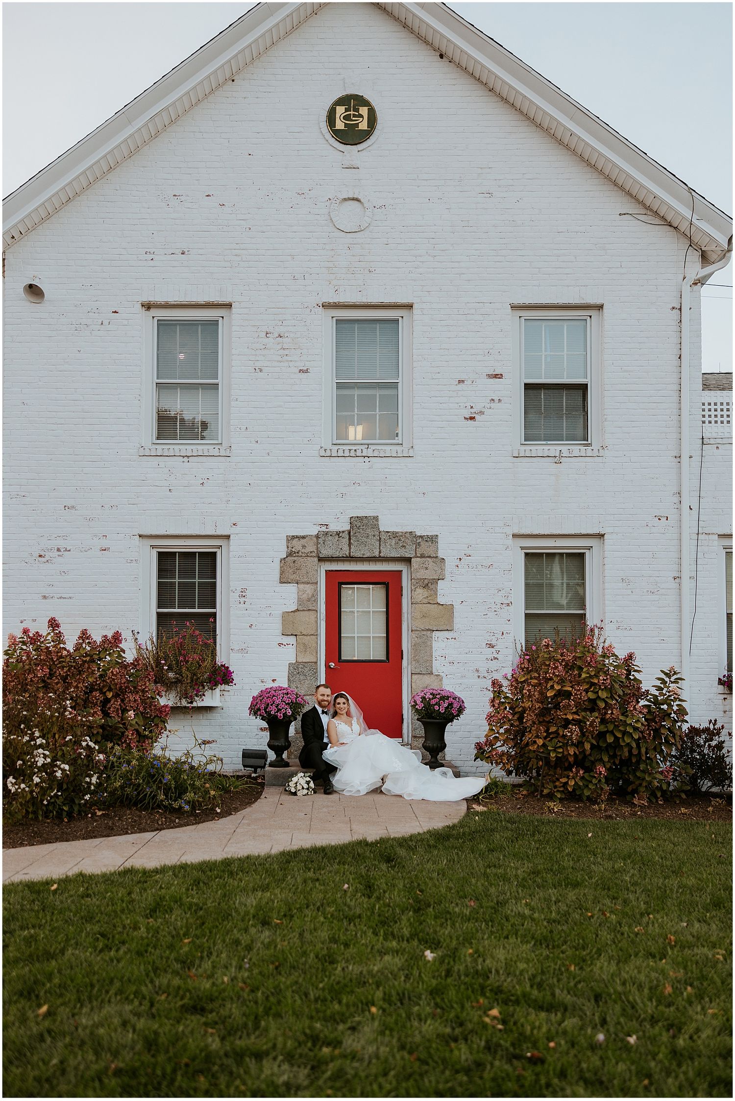 White historic building with red door and pink floral decorations.