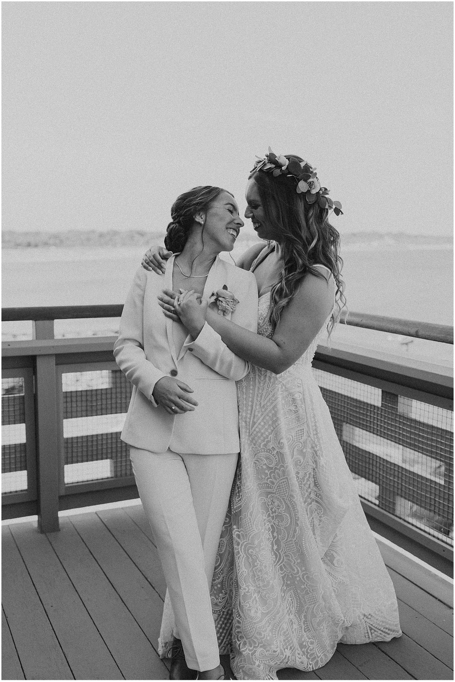 Two people sharing intimate laughter on a wooden deck by the water.