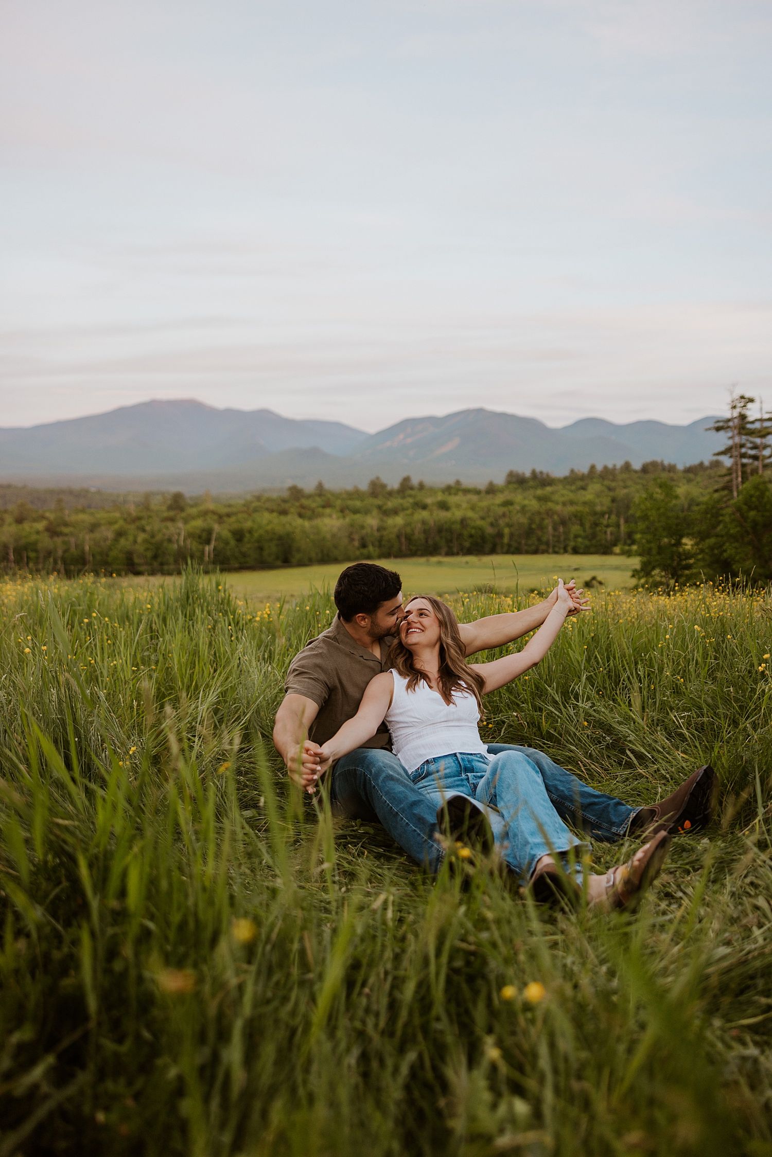 New Hampshire couple laying in a wildflower field in the White Mountains taking engagement pictures