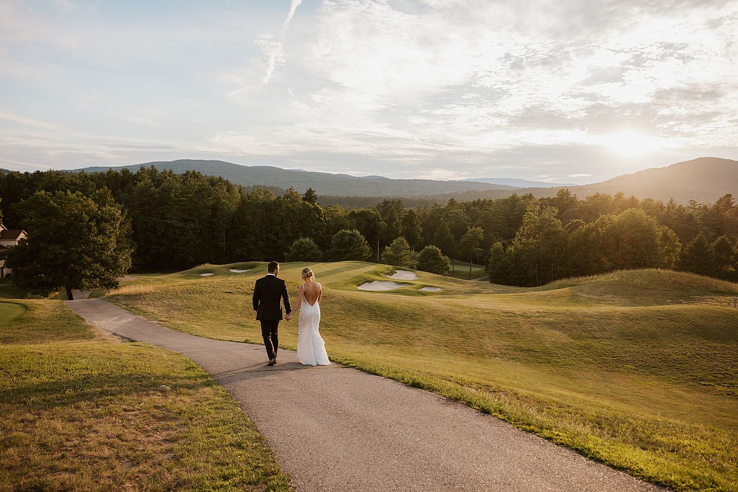 Bride and groom walking the property of the Owl's Nest Resort in NH at sunset