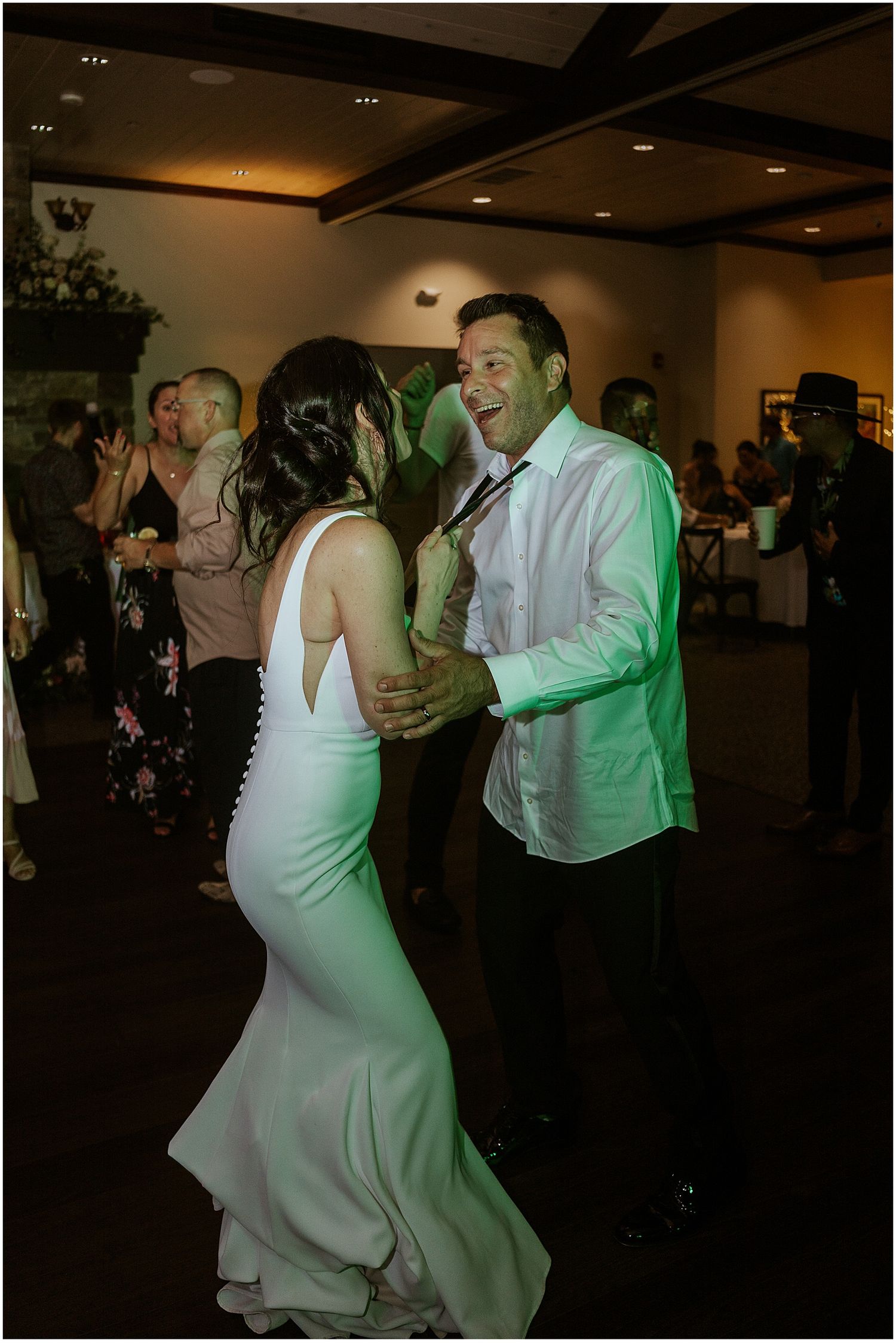 Couple sharing an intimate dance moment under moody reception lighting.