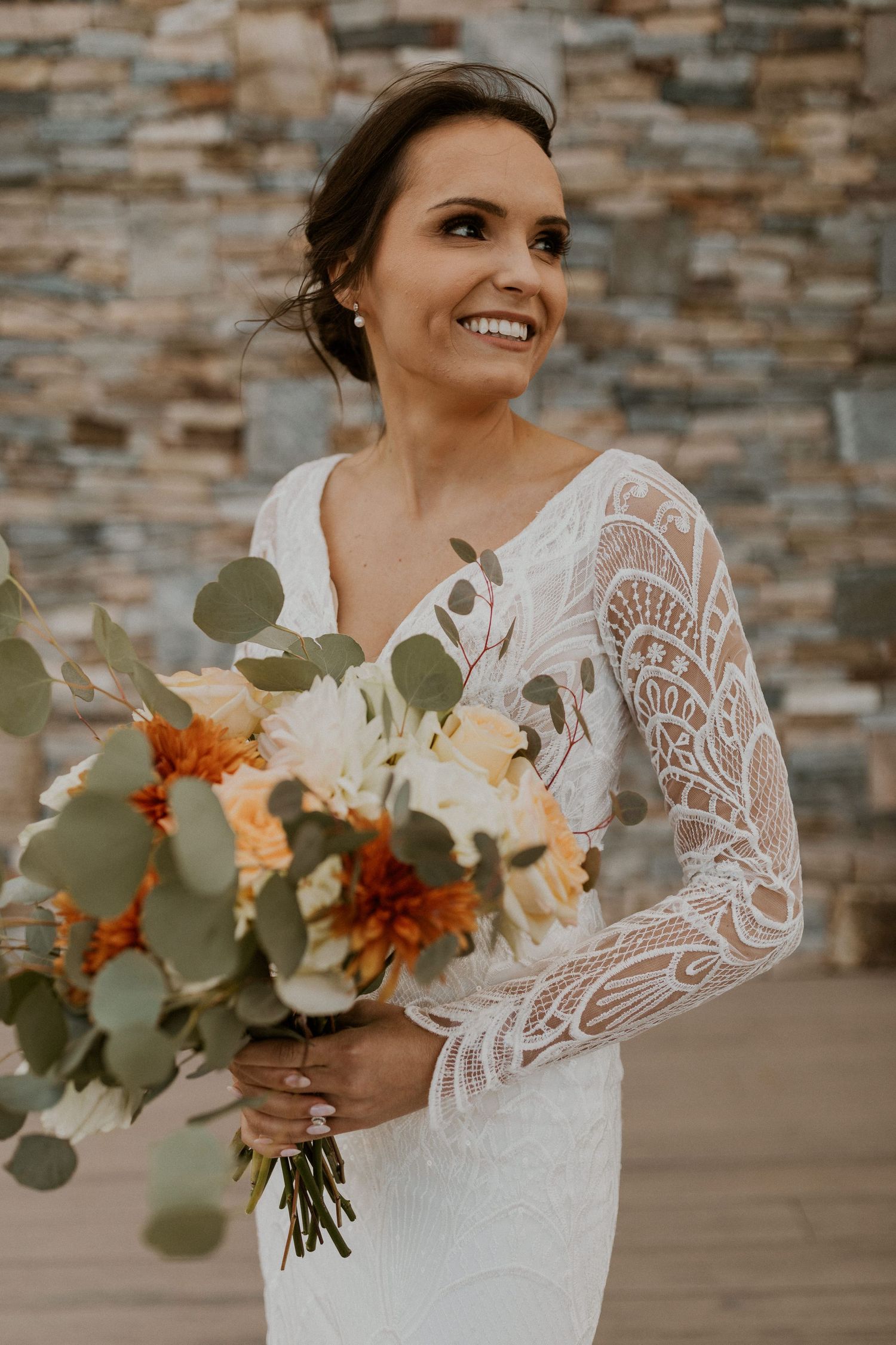 The stunning bride, Abbie, in front of the stonework of the Lake House buildling.