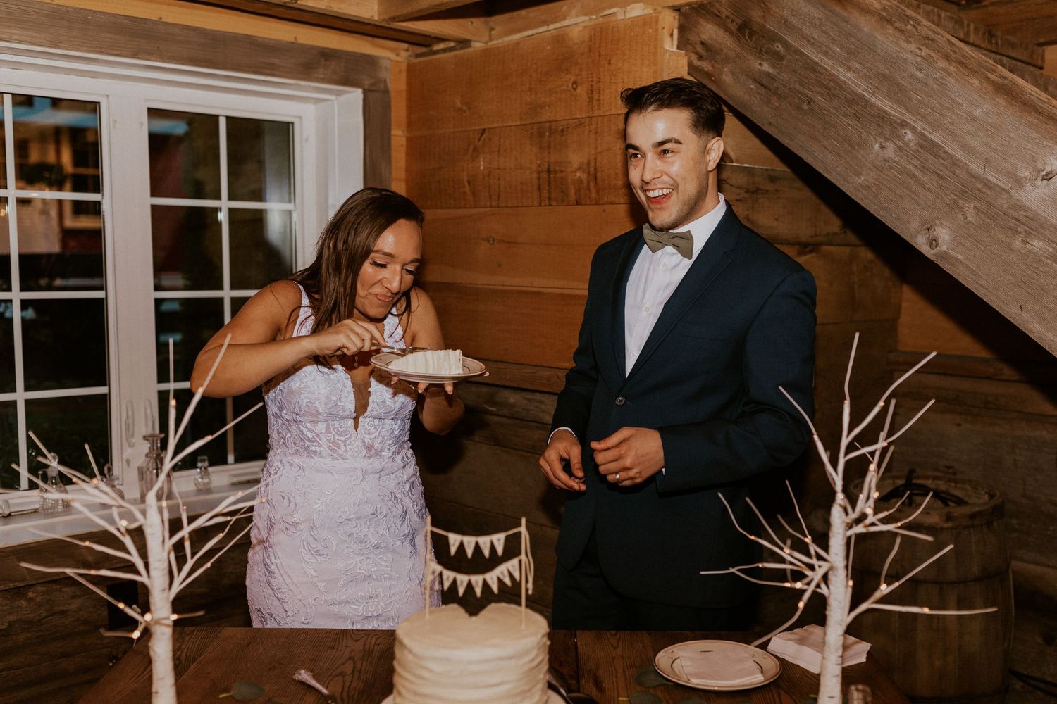 Couple shares an intimate moment during their first dance in a rustic wooden barn venue with decorative lights.