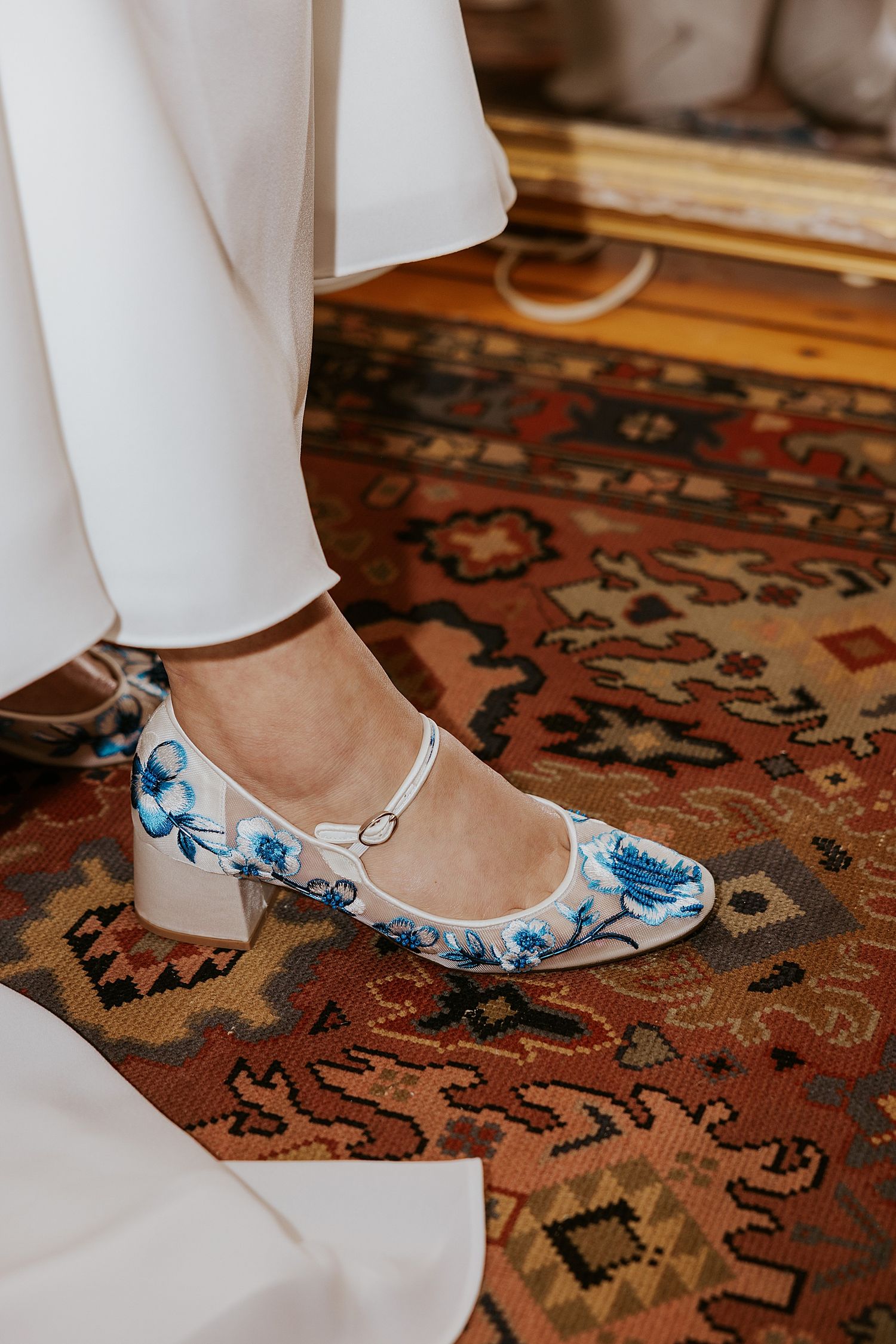 White sheer bridal shoed with blue flowers embroidered on them