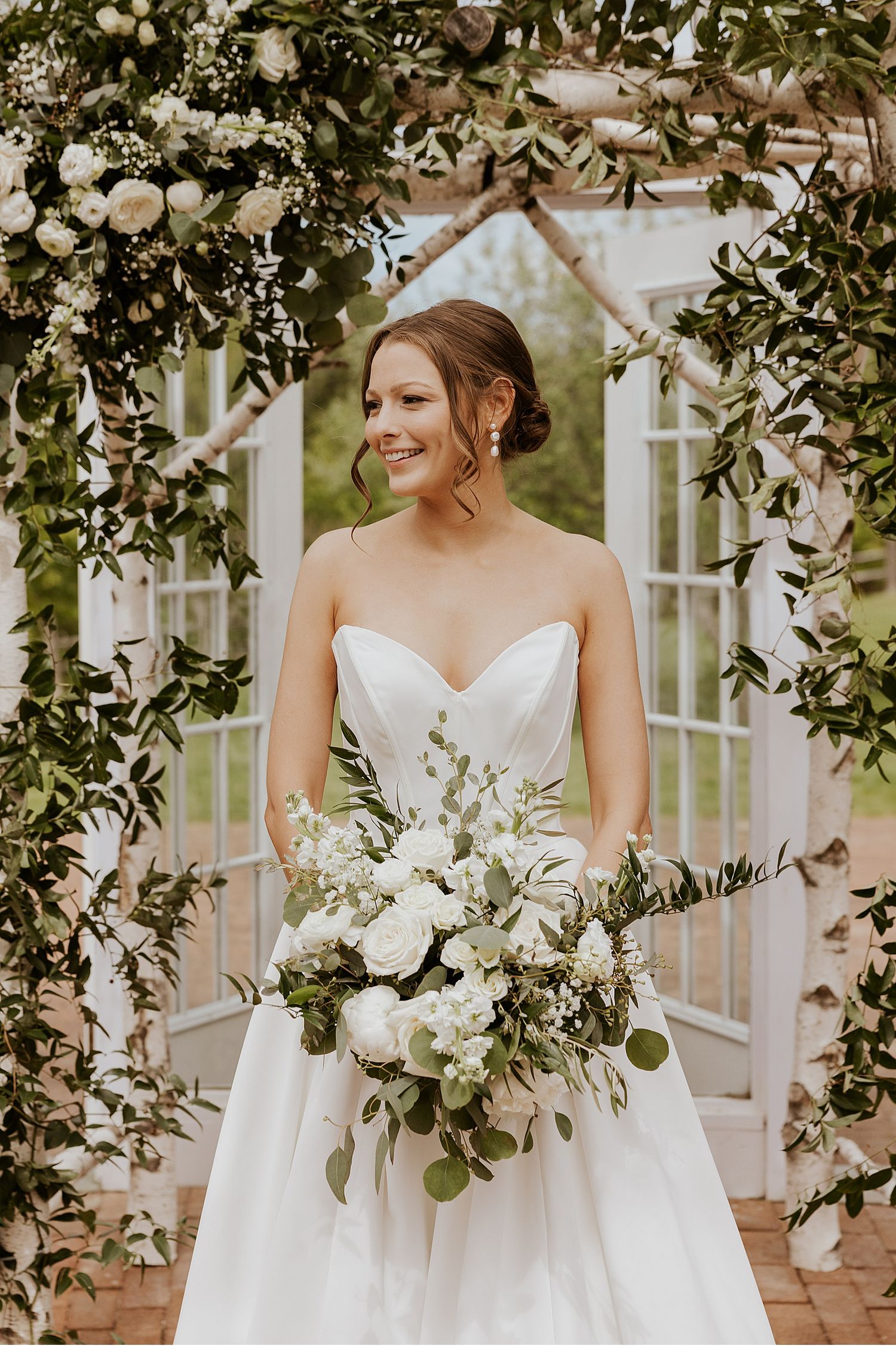 Elegant white wedding dress details with floral bouquets in a garden setting.