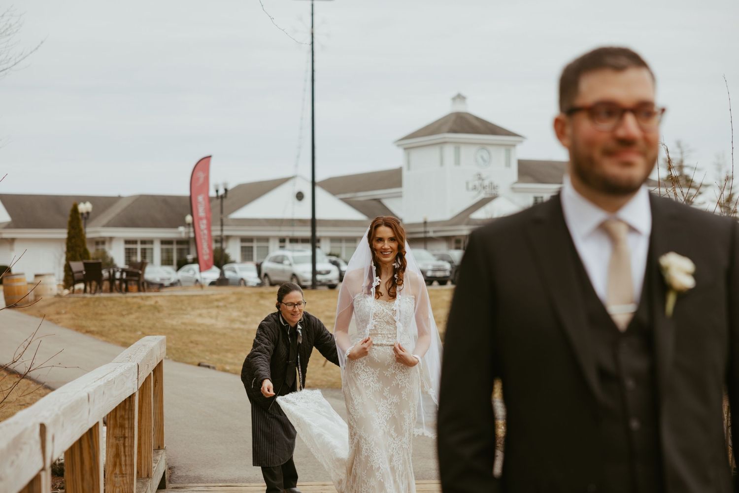 Wedding party walking on a wooden boardwalk with a white lighthouse-style building in the background.