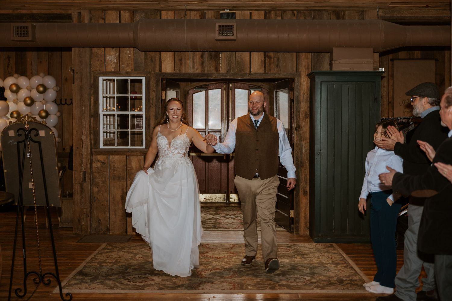Wedding celebration inside a rustic barn venue with wooden beams and warm lighting.
