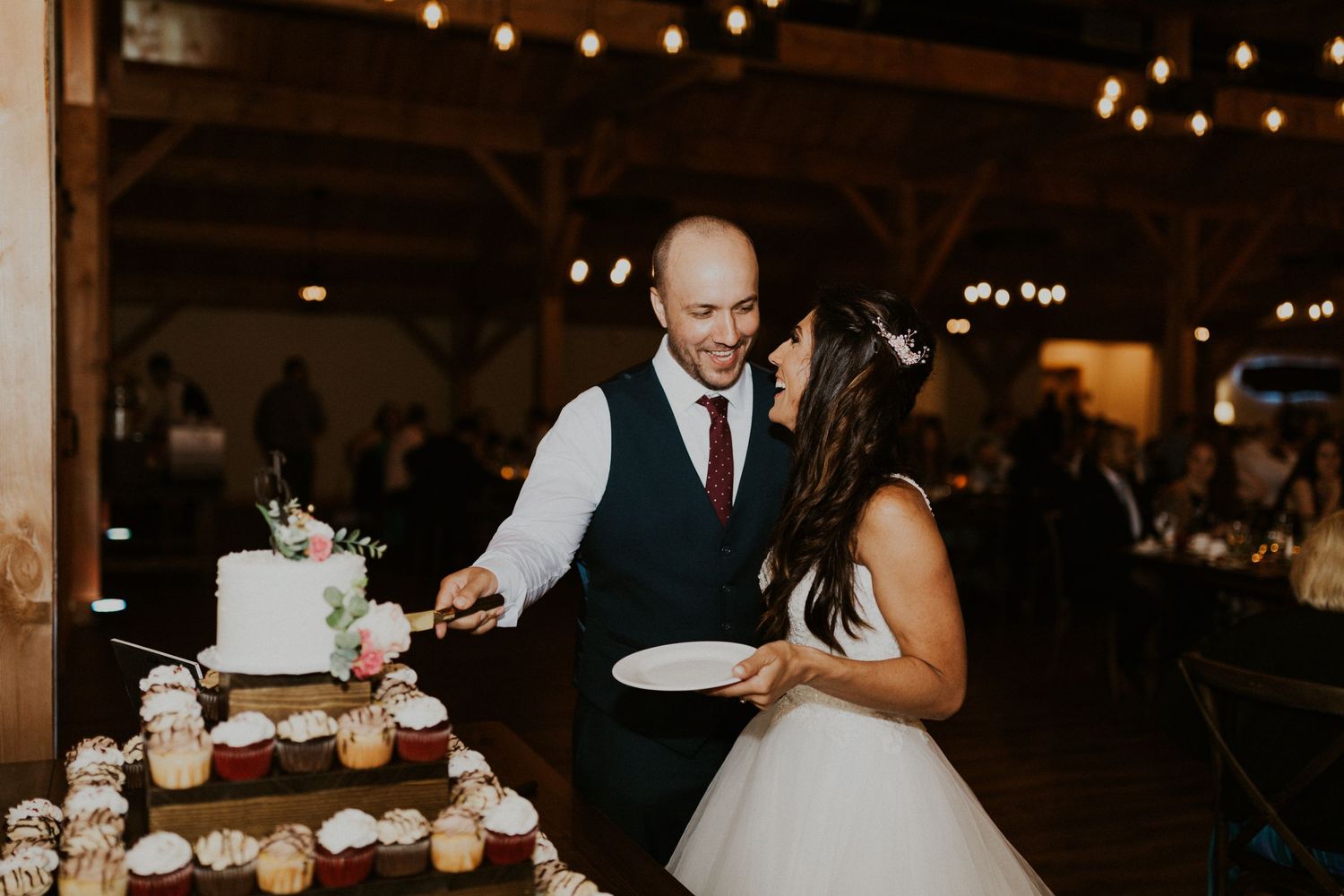 Wedding party dancing and celebrating on a rustic dance floor under string lights.
