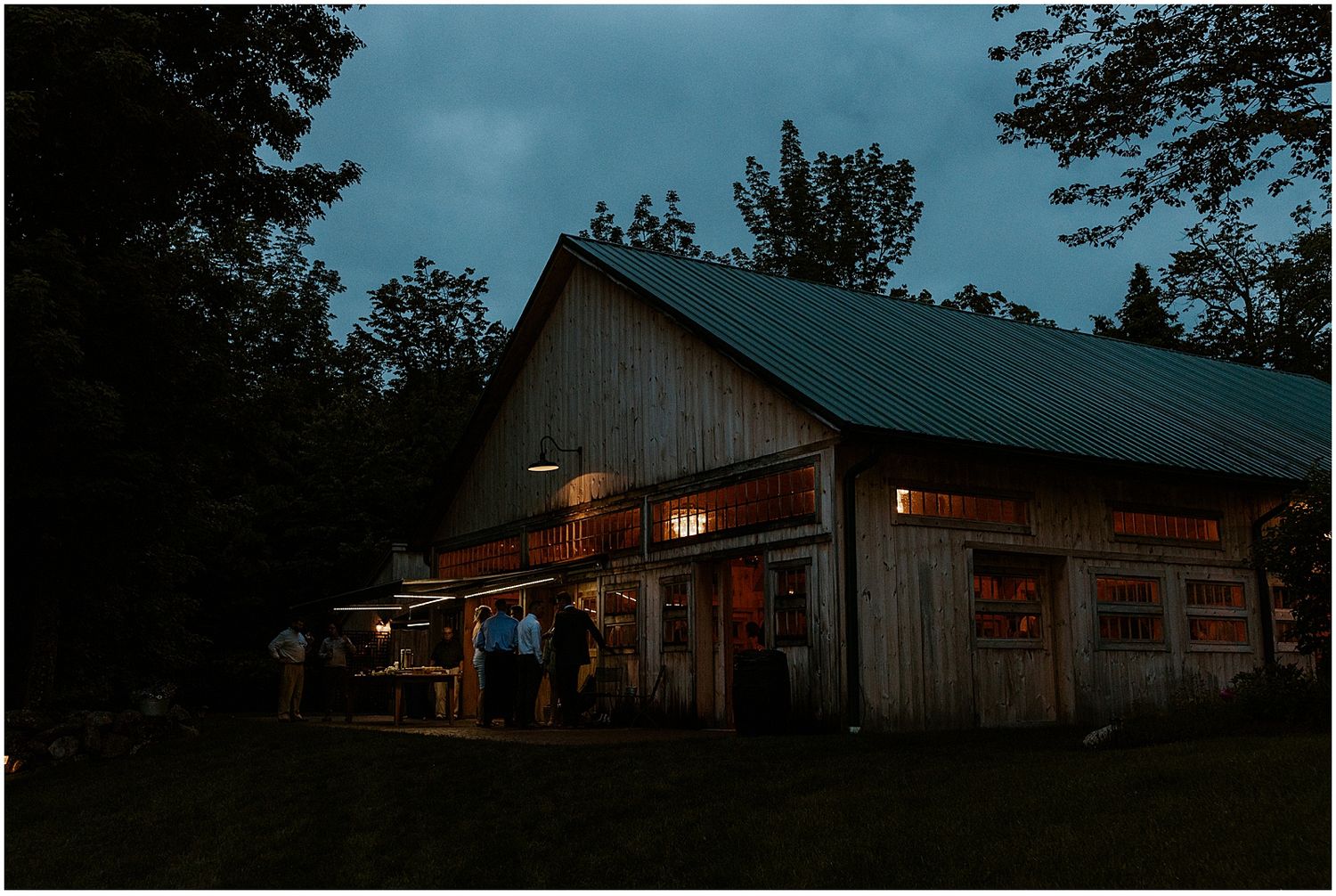 Rustic barn wedding venue exterior at dusk with ambient lighting.