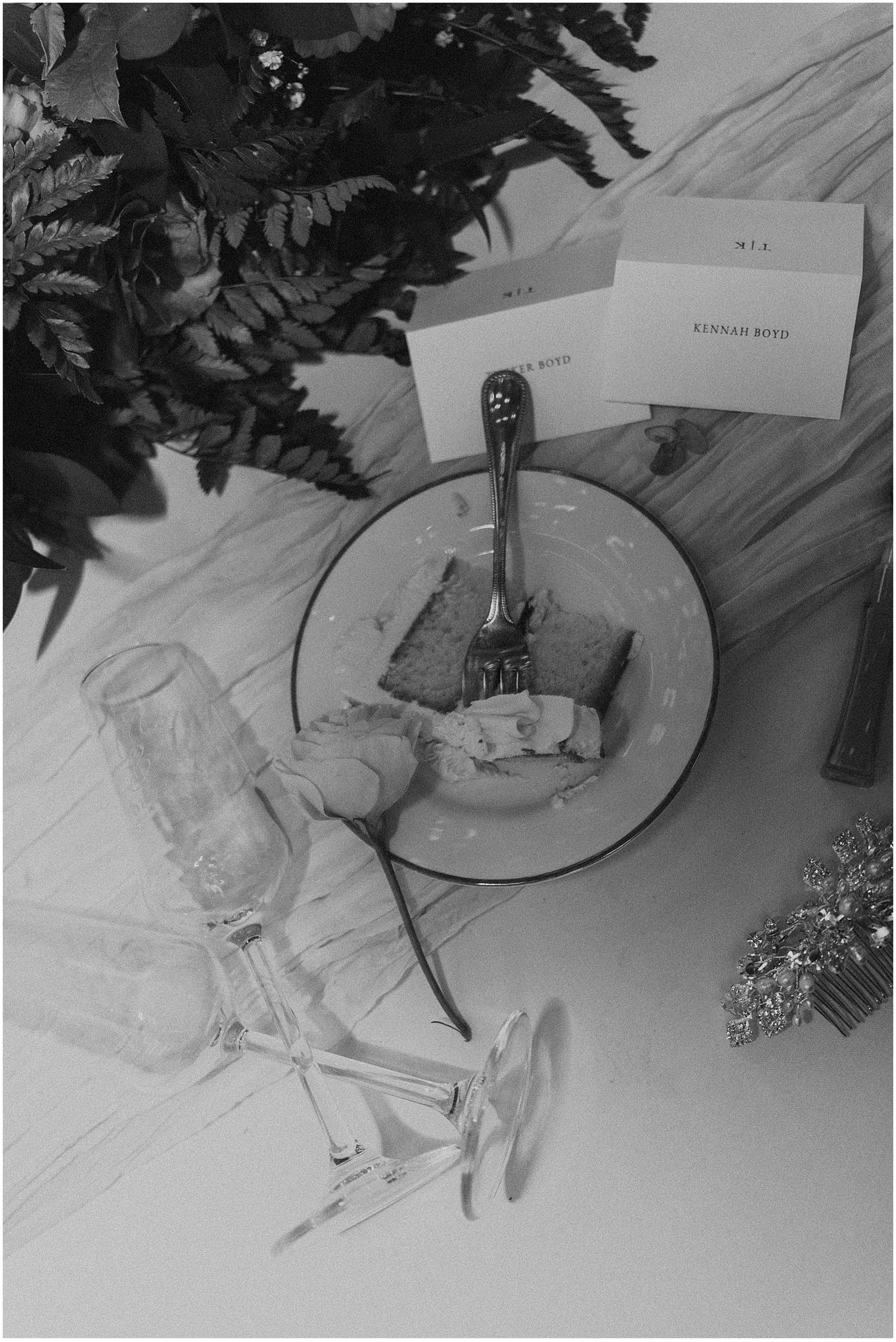 Black and white photo of place settings and table decor at a wedding reception.