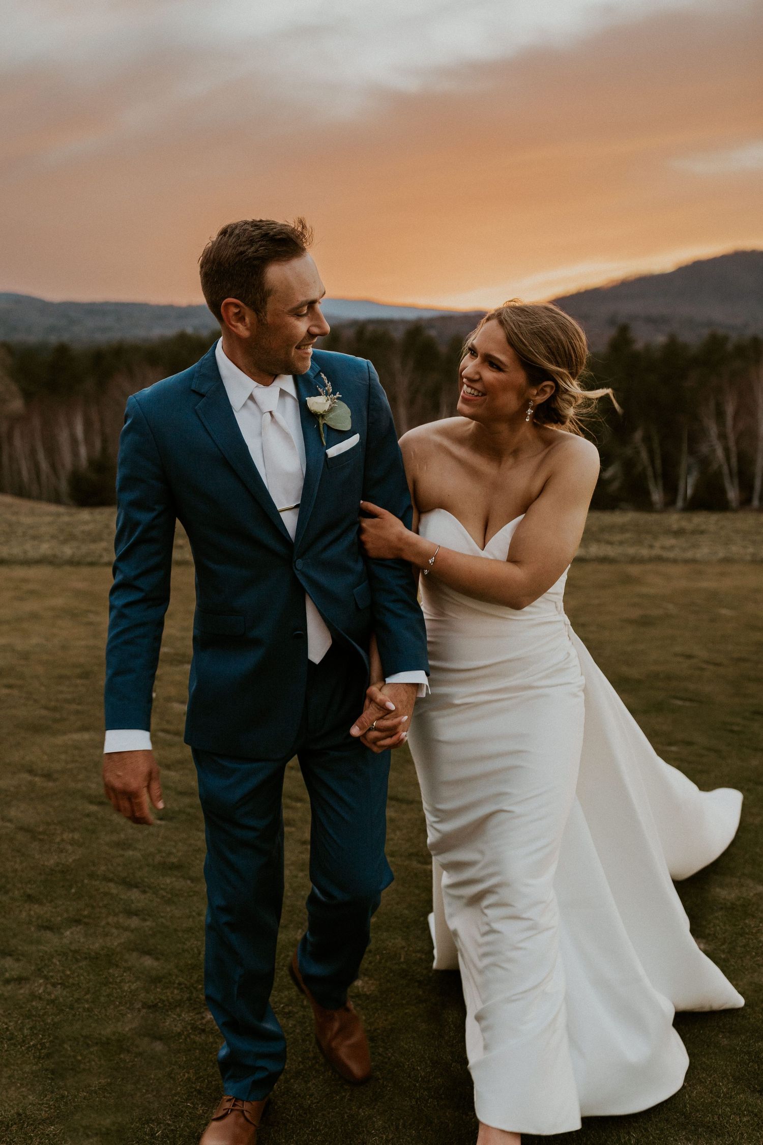 Kendra and Andrew walking together playfully during sunset after their wedding at Owl's Nest Resort in Thornton NH.