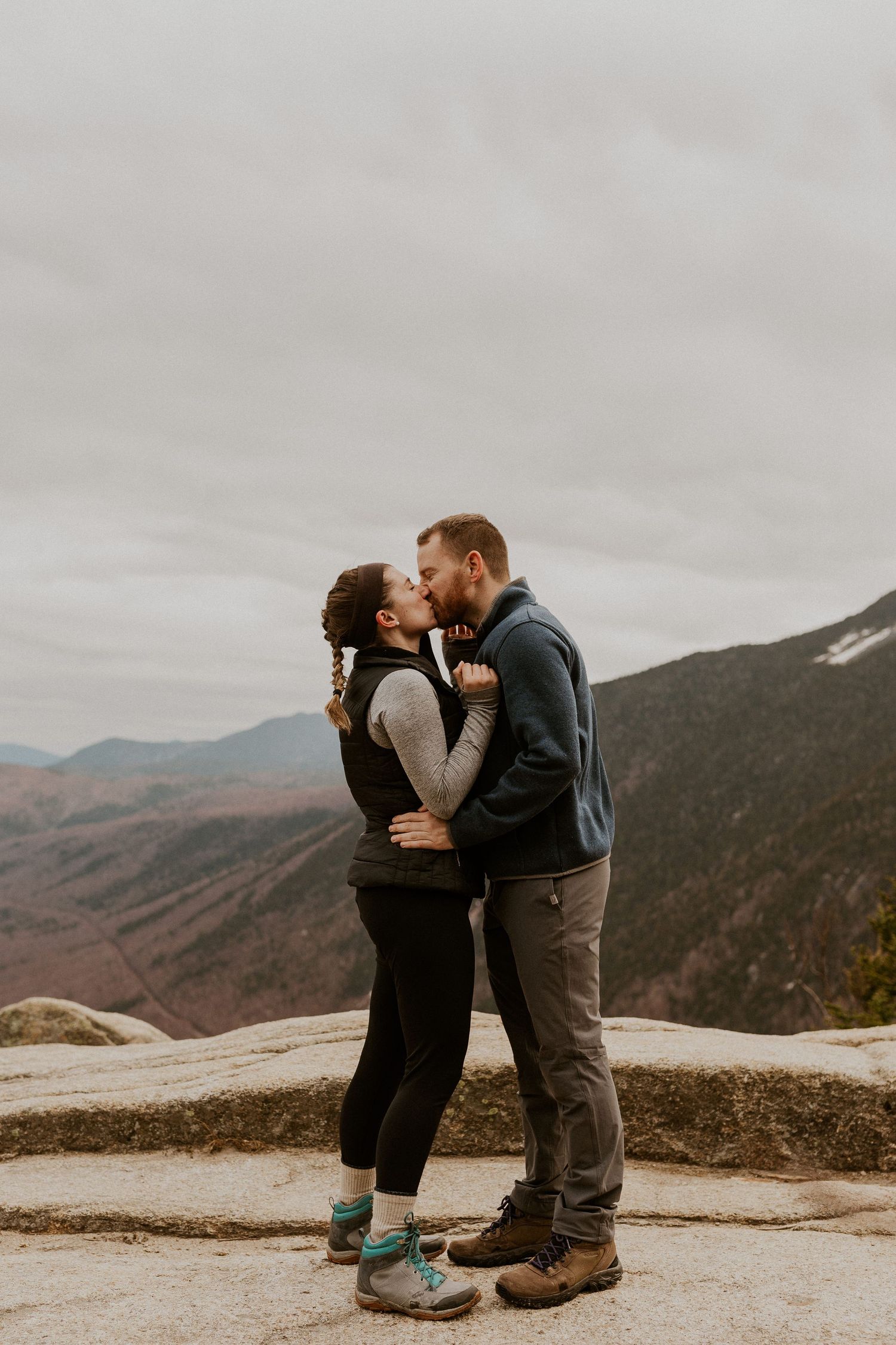 Newly engaged couple kissing on the summit of Mount Willard just after he proposed to her.