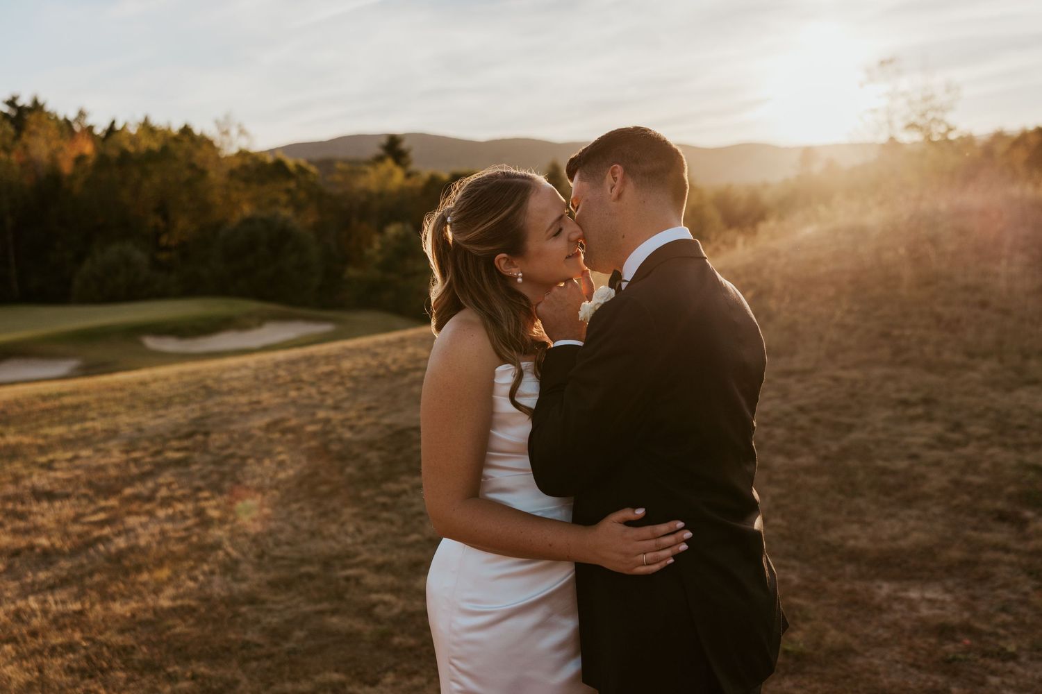 Bride and groom share a romantic moment at golden hour on a scenic golf course with mountain views.