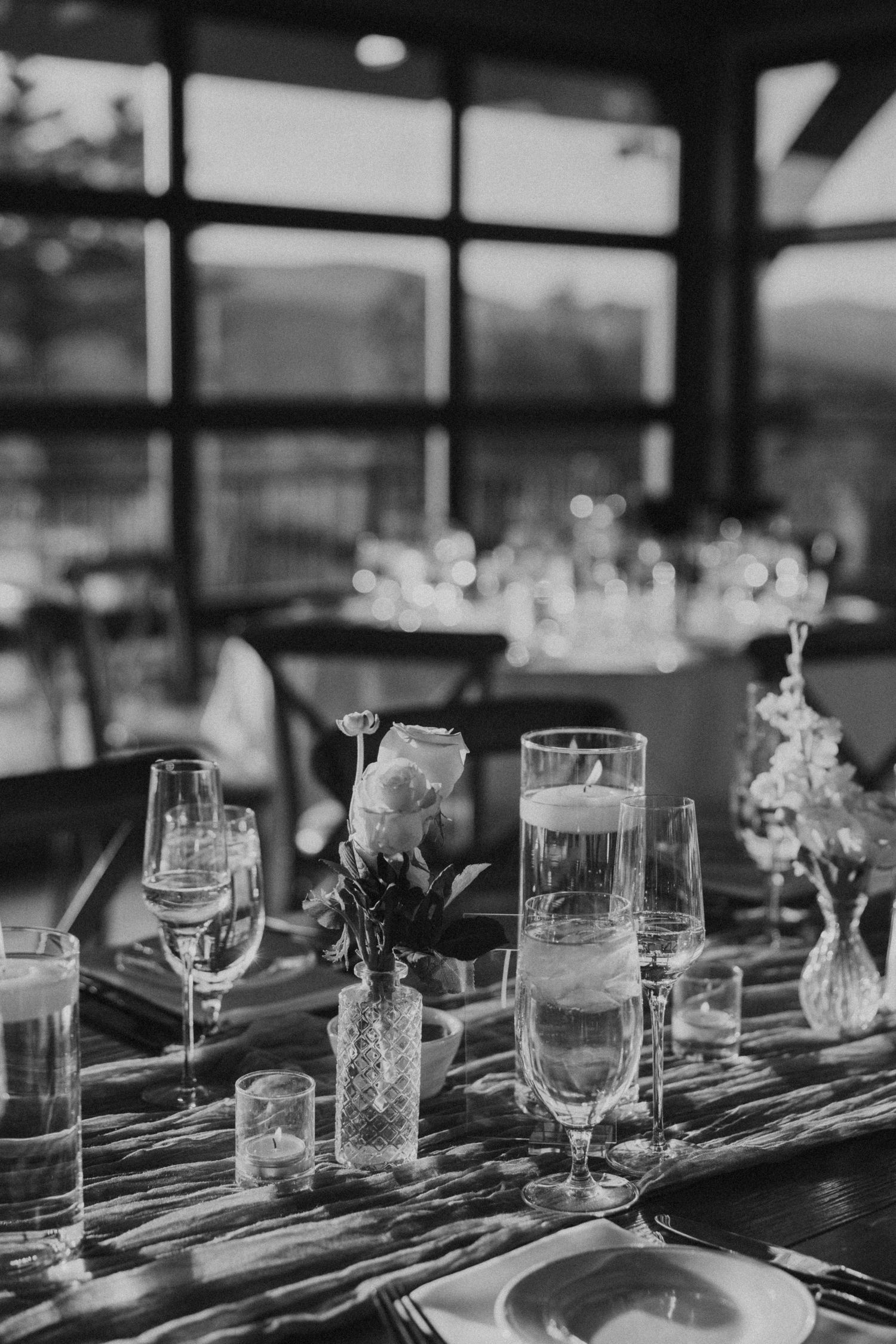 Elegant black and white wedding reception table setting with candles, glassware, and floral accents.