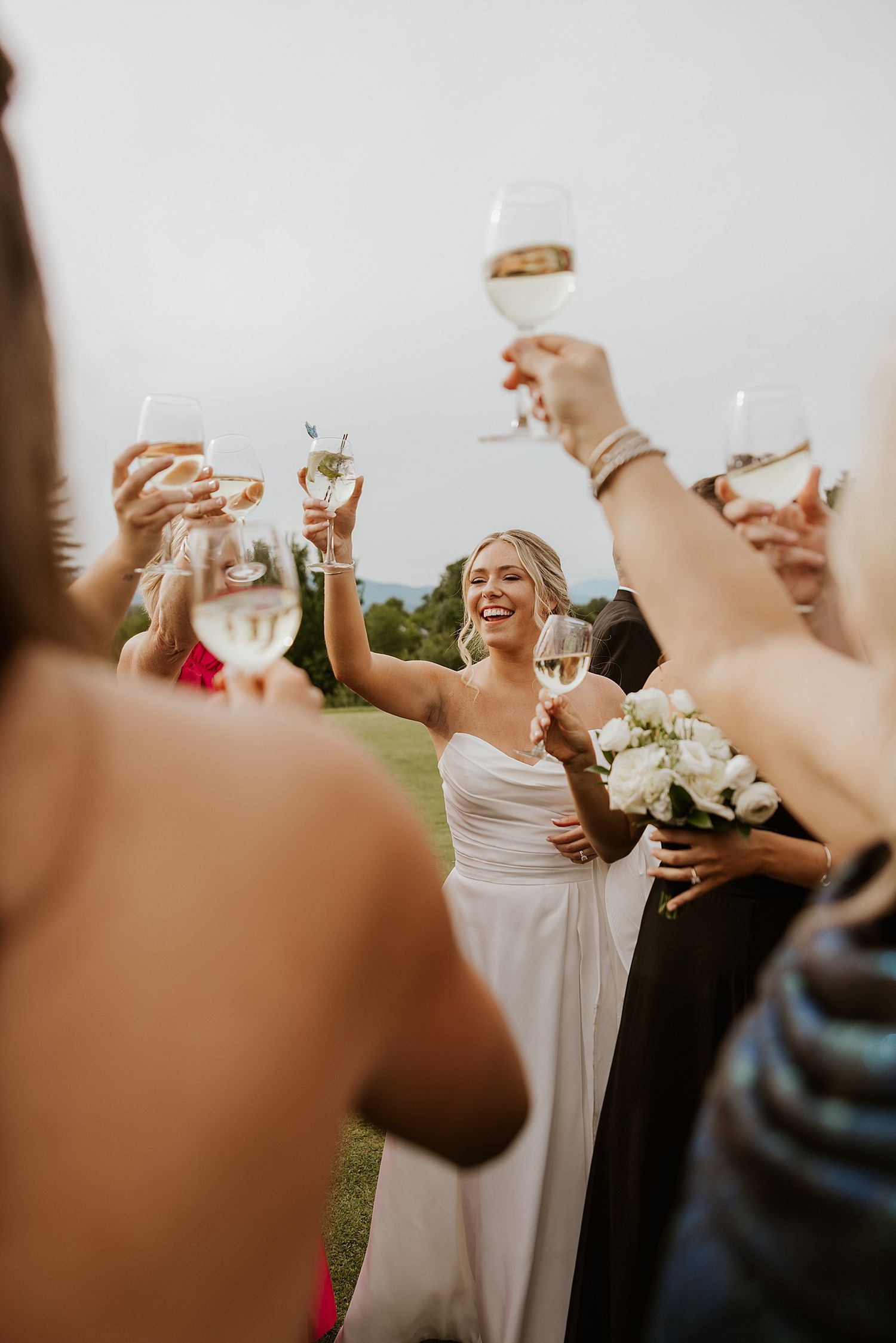 Bride laughing and toasting with her guests at cocktail hour at her New Hampshire wedding