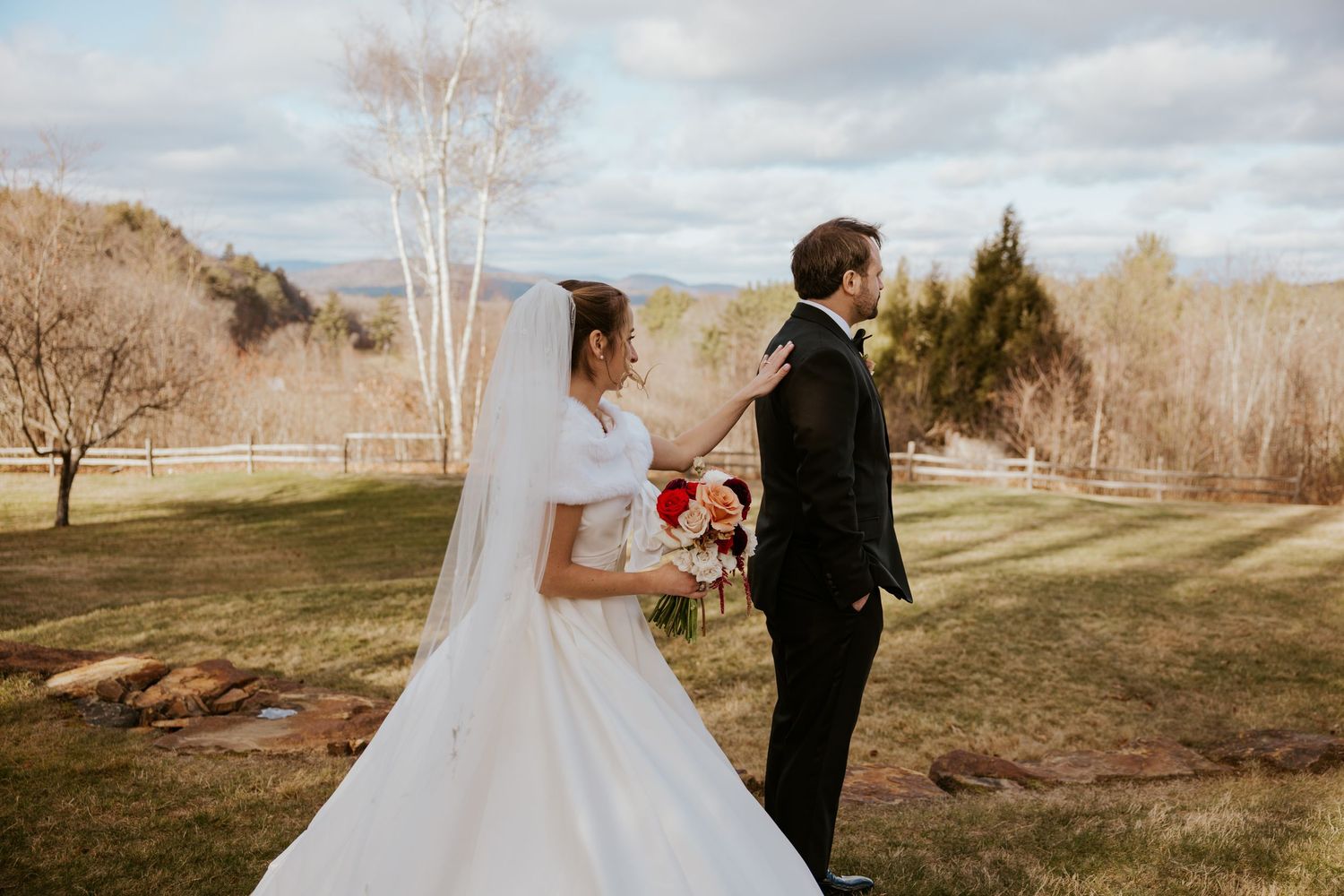Bride and groom share a first look moment outdoors on a green lawn with scenic mountain views.